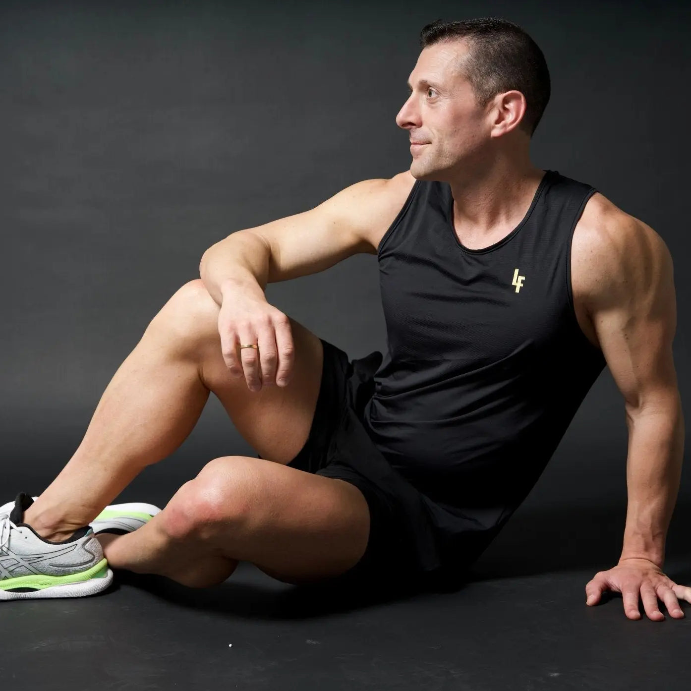 Modelo sentado en pose artística con camiseta técnica sin mangas MAN-U de LUXFEEL en color Negro, diseñada para un alto rendimiento.