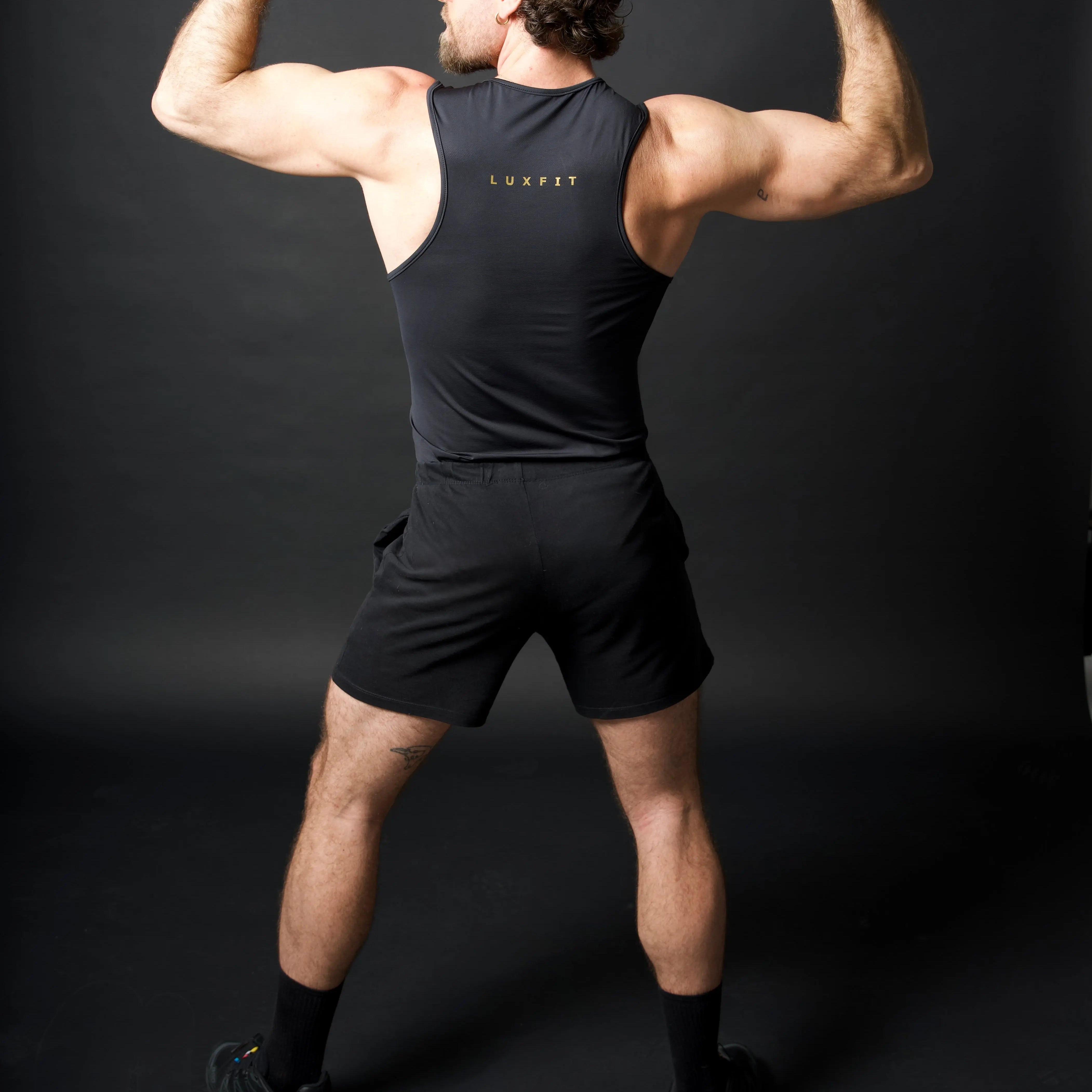 Hombre de espaldas vistiendo la camiseta técnica sin mangas MAN-U de LUXFEEL en color Negro