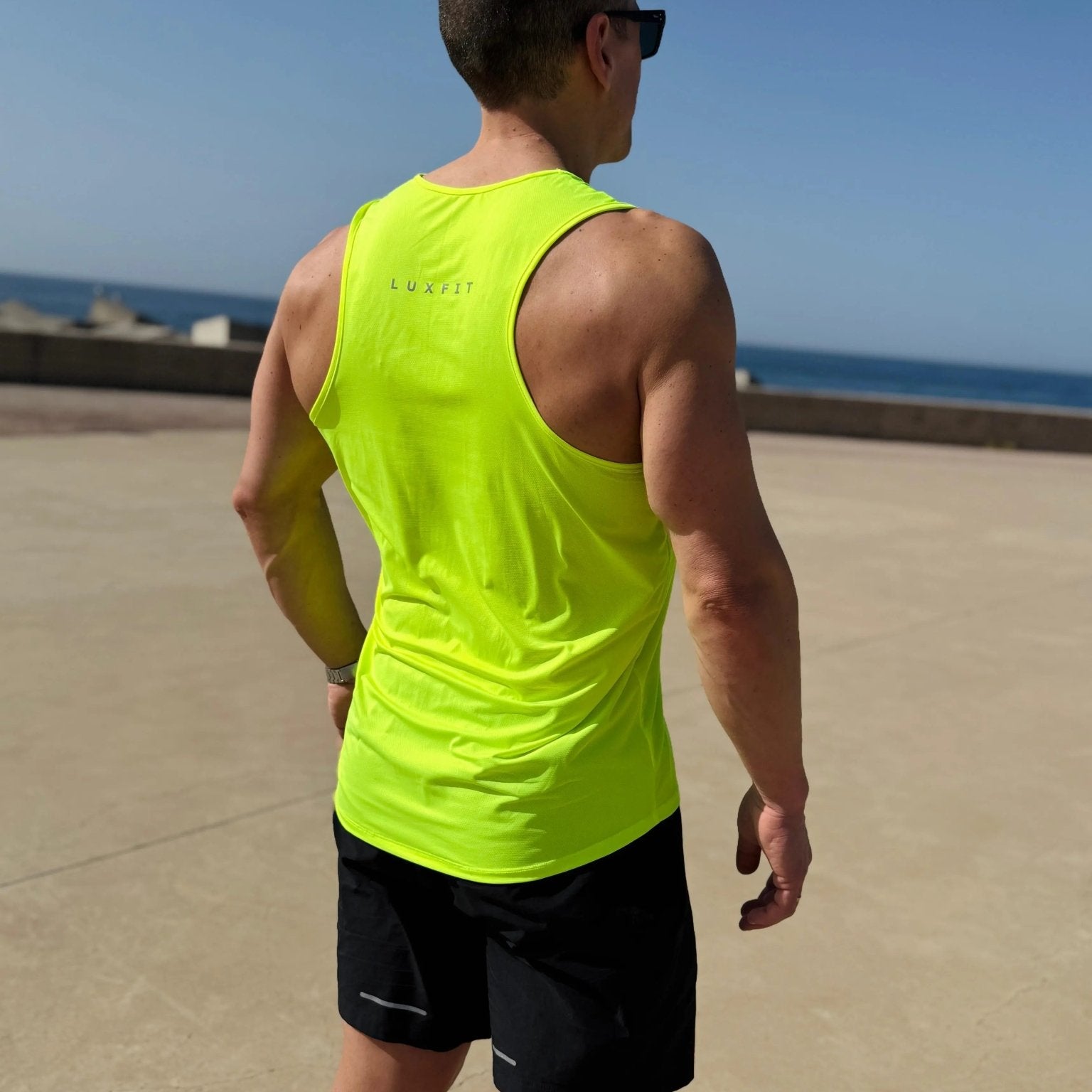 Hombre de espaldas en el exterior vistiendo la camiseta técnica sin mangas MAN-U de LUXFEEL en color Amarillo, diseñada para un alto rendimiento.