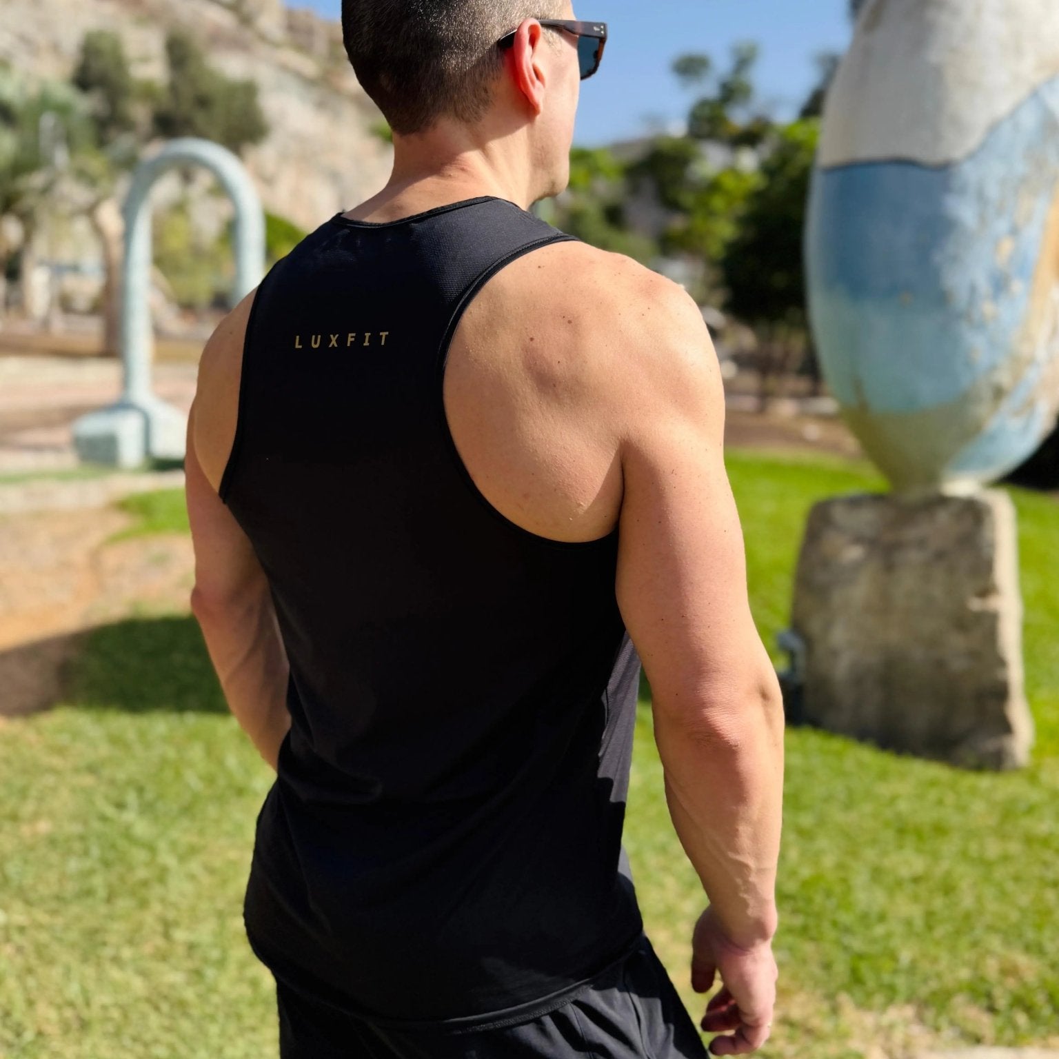 Modelo en el exterior vistiendo la camiseta técnica sin mangas MAN-U de LUXFEEL en color Negro, diseñada para un alto rendimiento.