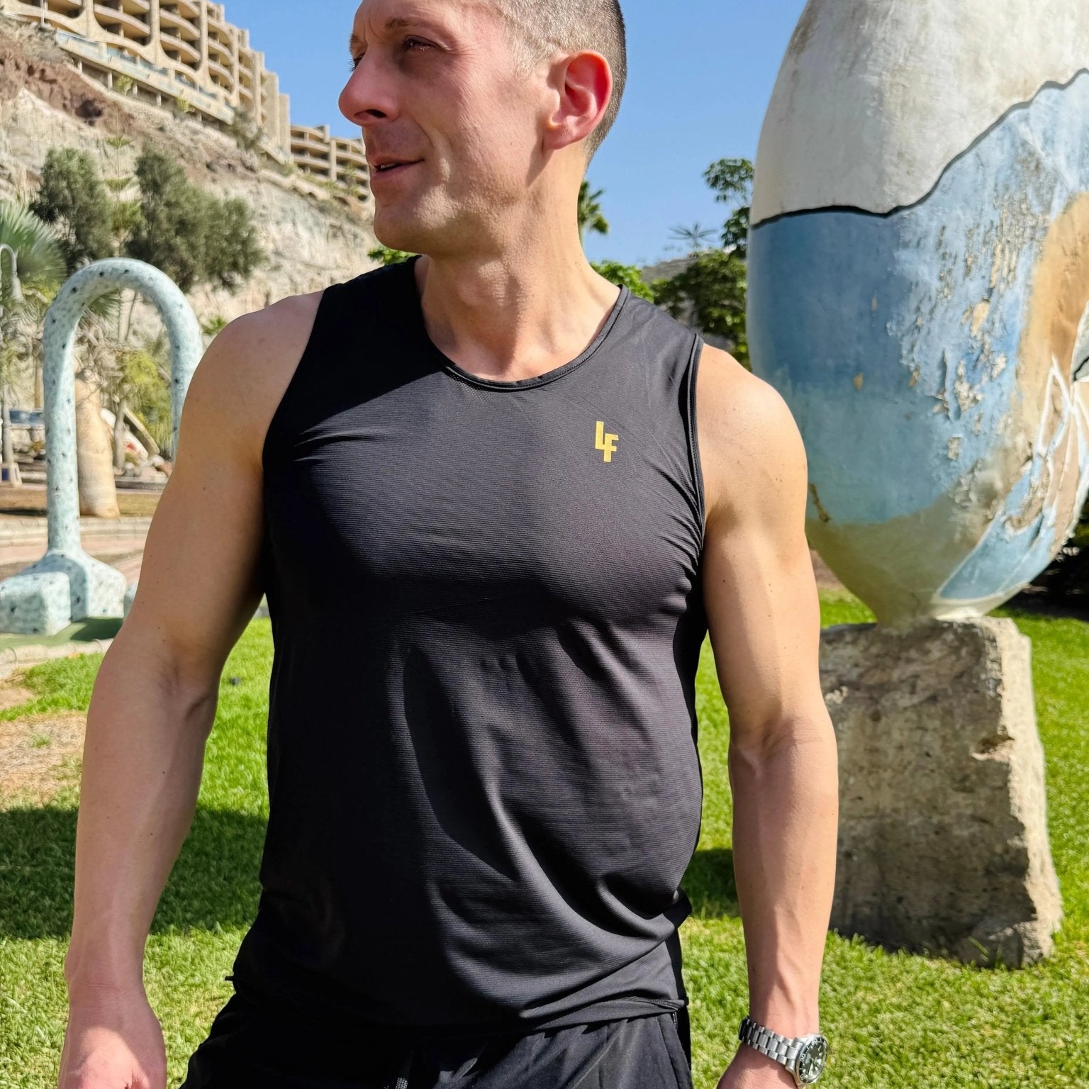 Modelo en el exterior vistiendo la camiseta técnica sin mangas MAN-U de LUXFEEL en color Negro, diseñada para un alto rendimiento.