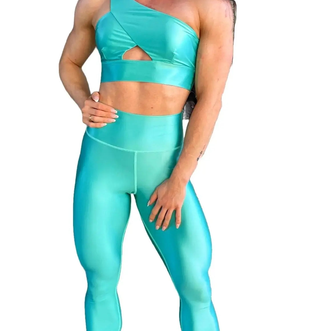 Mujer vistiendo el conjunto azul celeste brillante de LUXFEEL, compuesto por el top asimétrico Carmela (un solo hombro y apertura en el escote) y el legging Pearl Shine a juego.