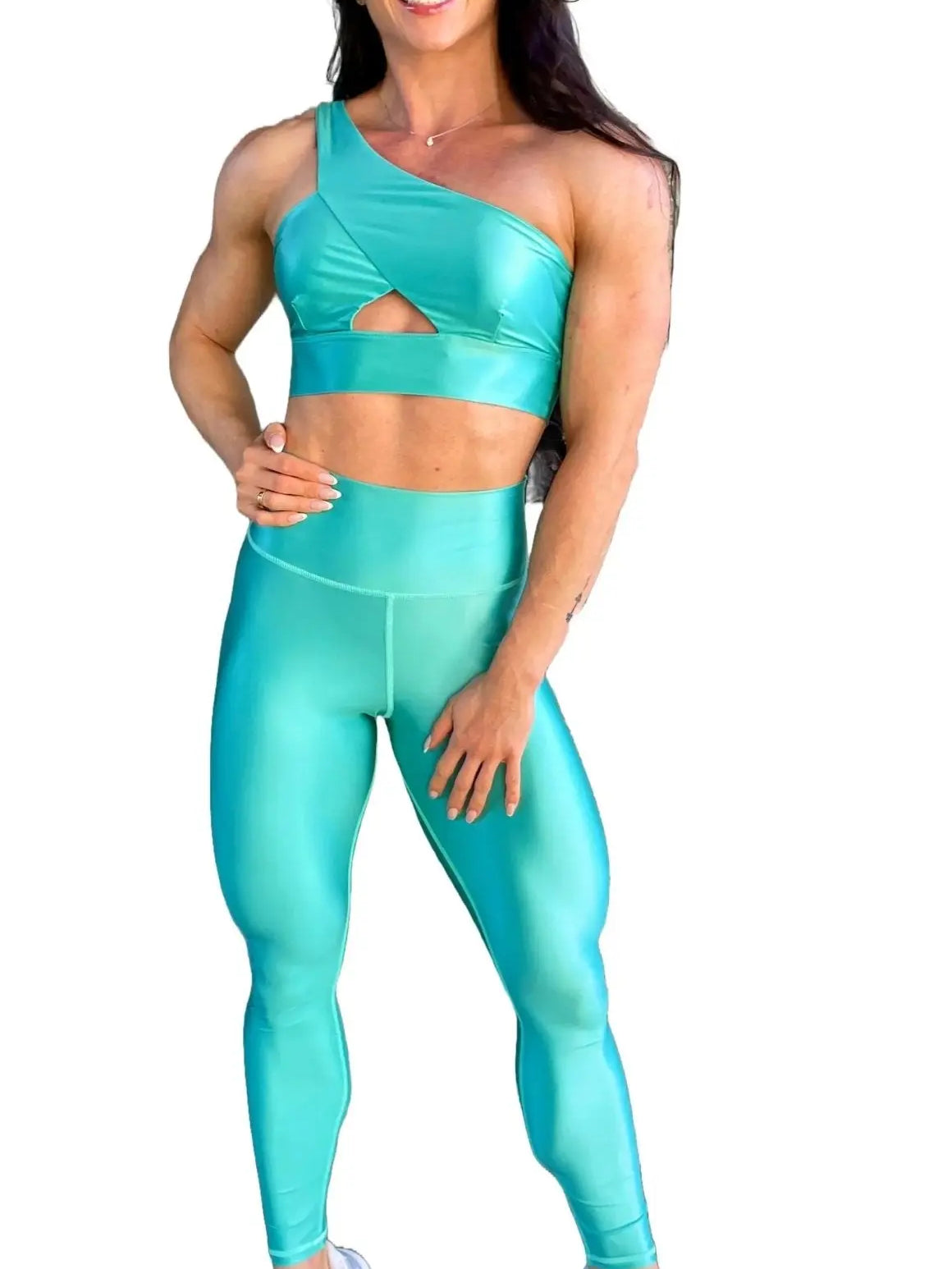 Mujer vistiendo el conjunto azul celeste brillante de LUXFEEL, compuesto por el top asimétrico Carmela (un solo hombro y apertura en el escote) y el legging Pearl Shine a juego.