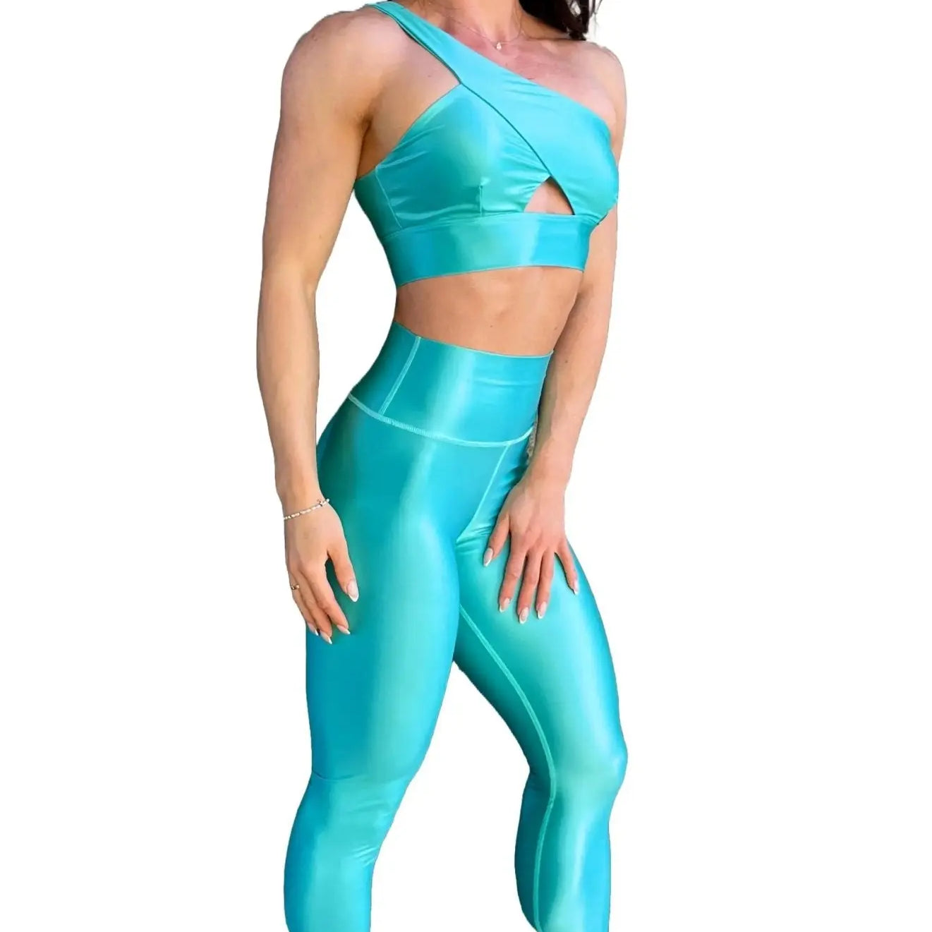 Mujer vistiendo el conjunto azul celeste brillante de LUXFEEL, compuesto por el top asimétrico Carmela (un solo hombro y apertura en el escote) y el legging Pearl Shine a juego.