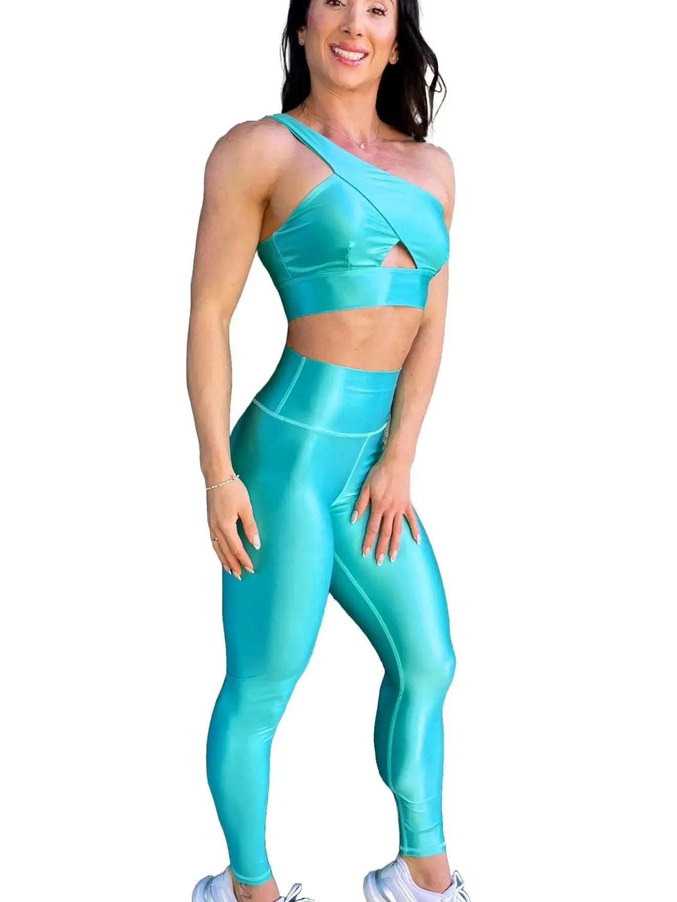 Mujer vistiendo el conjunto azul celeste brillante de LUXFEEL, compuesto por el top asimétrico Carmela (un solo hombro y apertura en el escote) y el legging Pearl Shine a juego.