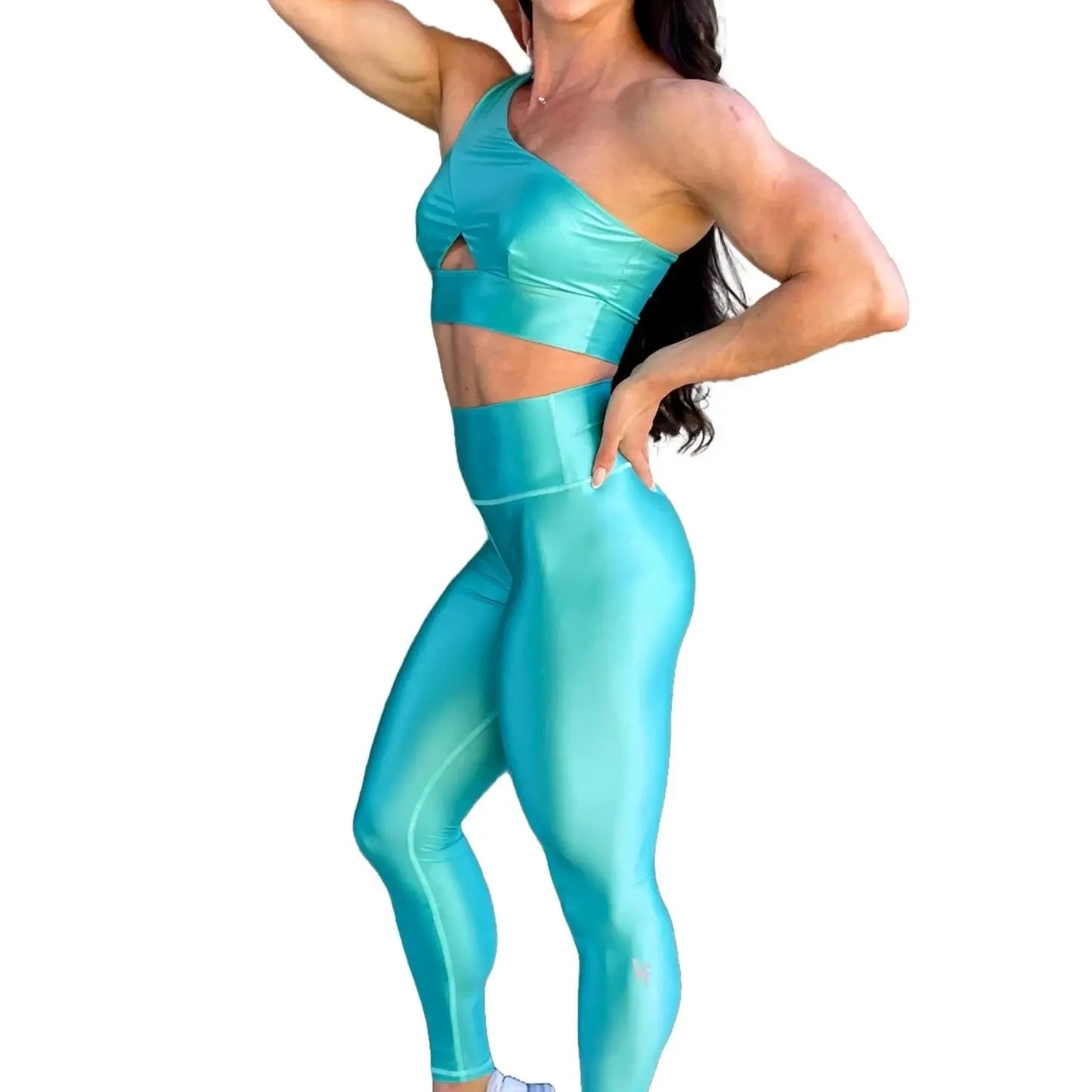 Mujer vistiendo el conjunto azul celeste brillante de LUXFEEL, compuesto por el top asimétrico Carmela (un solo hombro y apertura en el escote) y el legging Pearl Shine a juego.