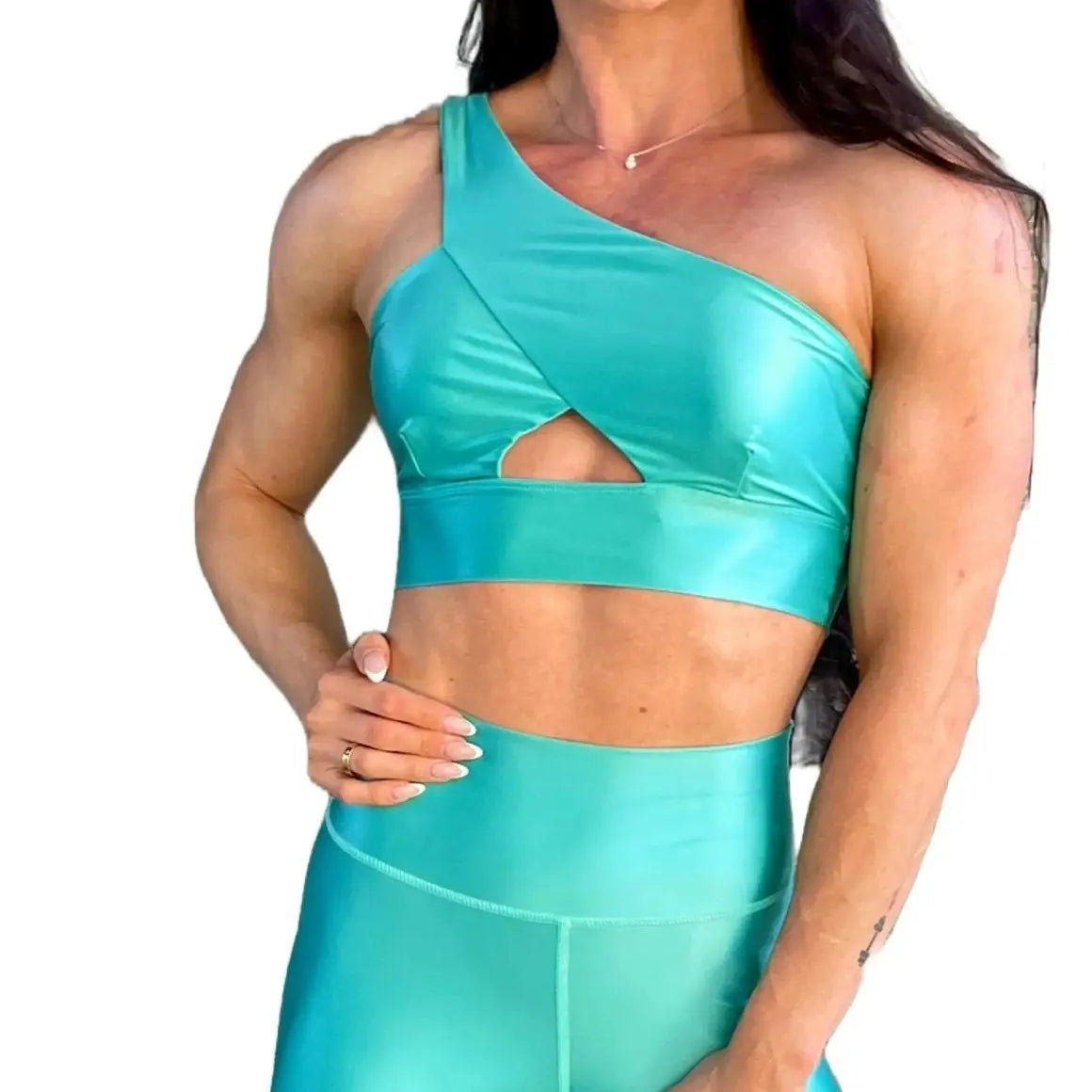 Mujer vistiendo el conjunto azul celeste brillante de LUXFEEL, compuesto por el top asimétrico Carmela (un solo hombro y apertura en el escote) y el legging Pearl Shine a juego.