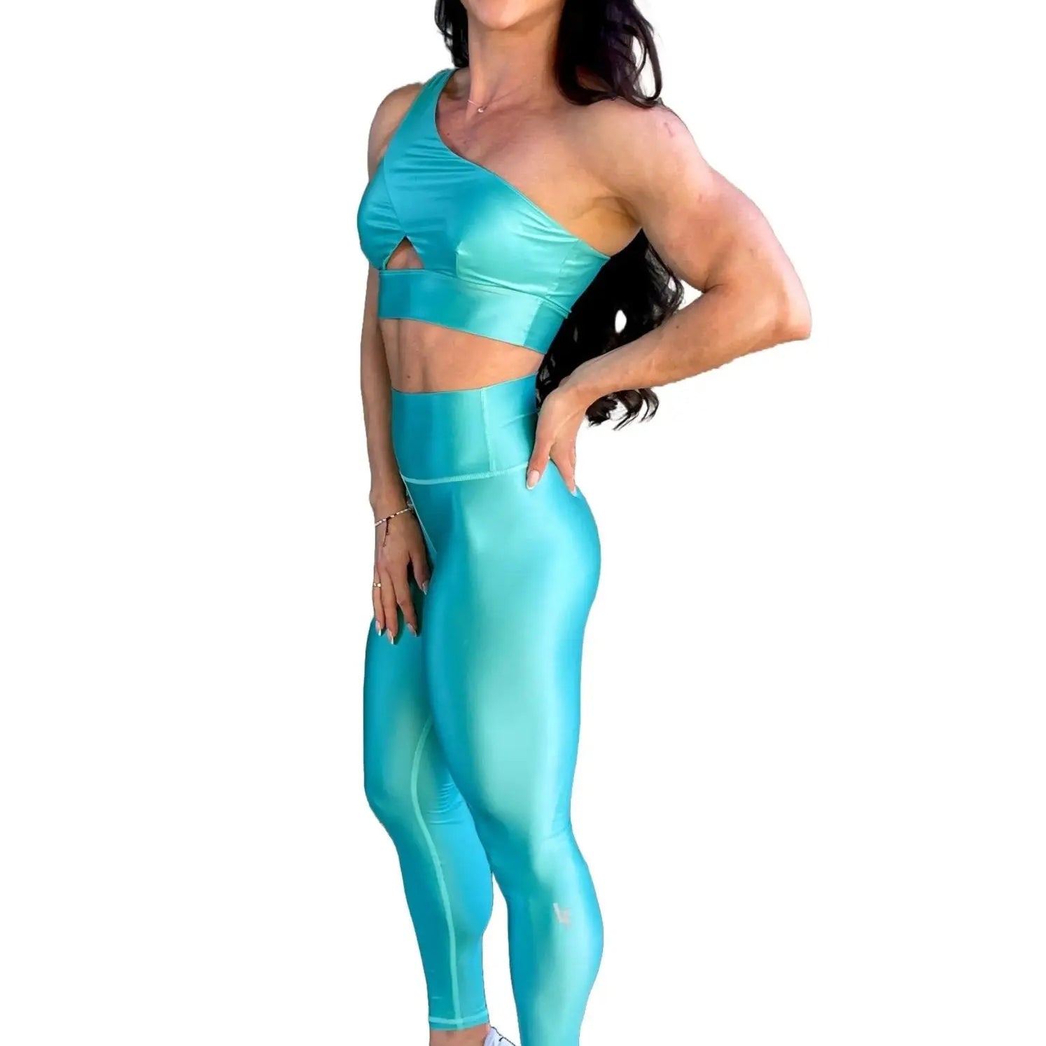 Mujer vistiendo el conjunto azul celeste brillante de LUXFEEL, compuesto por el top asimétrico Carmela (un solo hombro y apertura en el escote) y el legging Pearl Shine a juego.