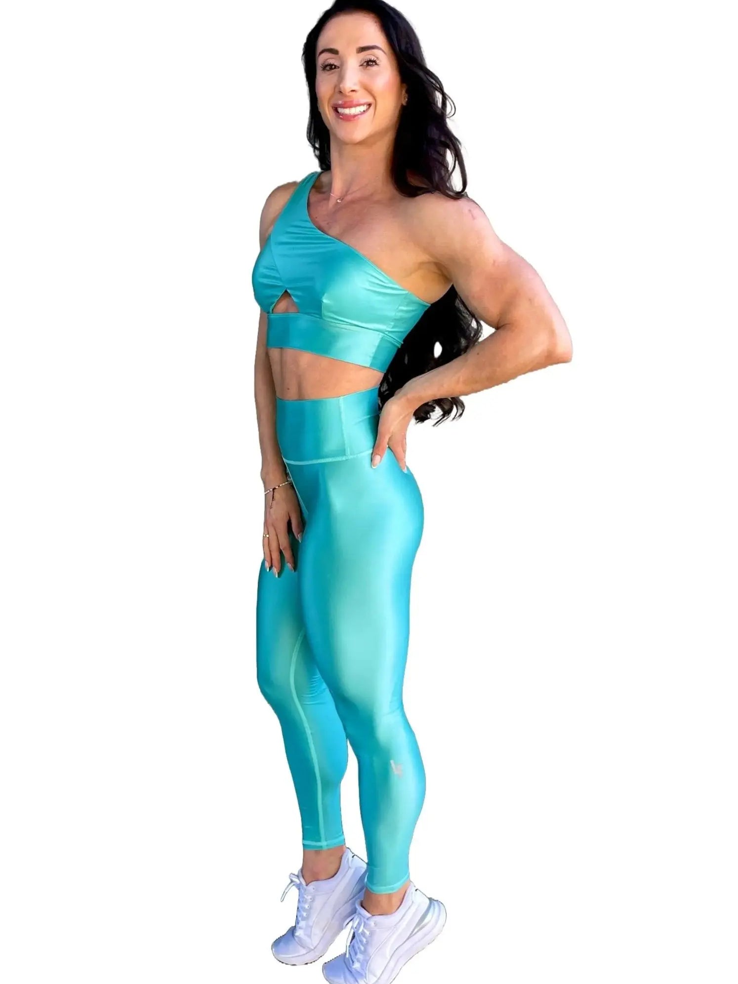 Mujer vistiendo el conjunto azul celeste brillante de LUXFEEL, compuesto por el top asimétrico Carmela (un solo hombro y apertura en el escote) y el legging Pearl Shine a juego.
