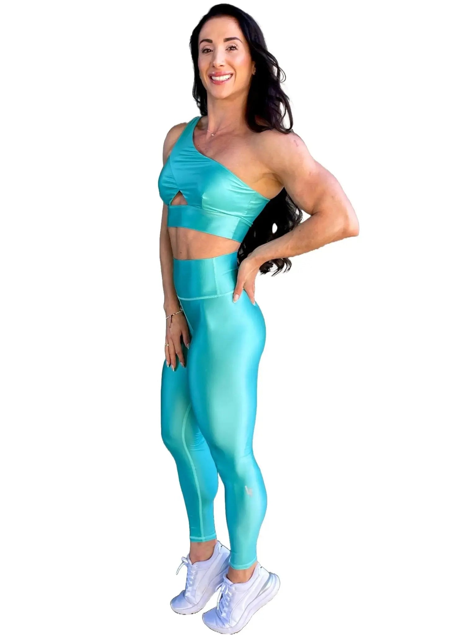 Mujer vistiendo el conjunto azul celeste brillante de LUXFEEL, compuesto por el top asimétrico Carmela (un solo hombro y apertura en el escote) y el legging Pearl Shine a juego.