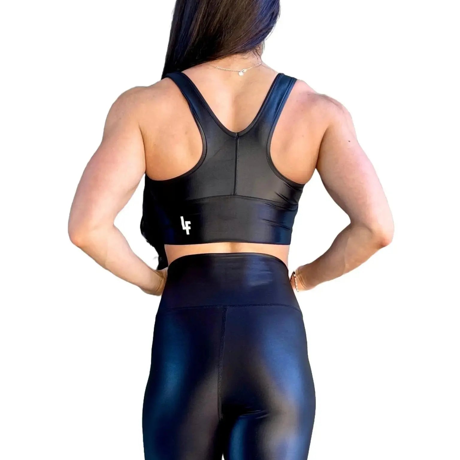 Mujer vistiendo el crop top brillante Top Adela Pearl Shine de LUXFEEL en color Negro Brillante, con escote en V y detalle fruncido en el pecho.