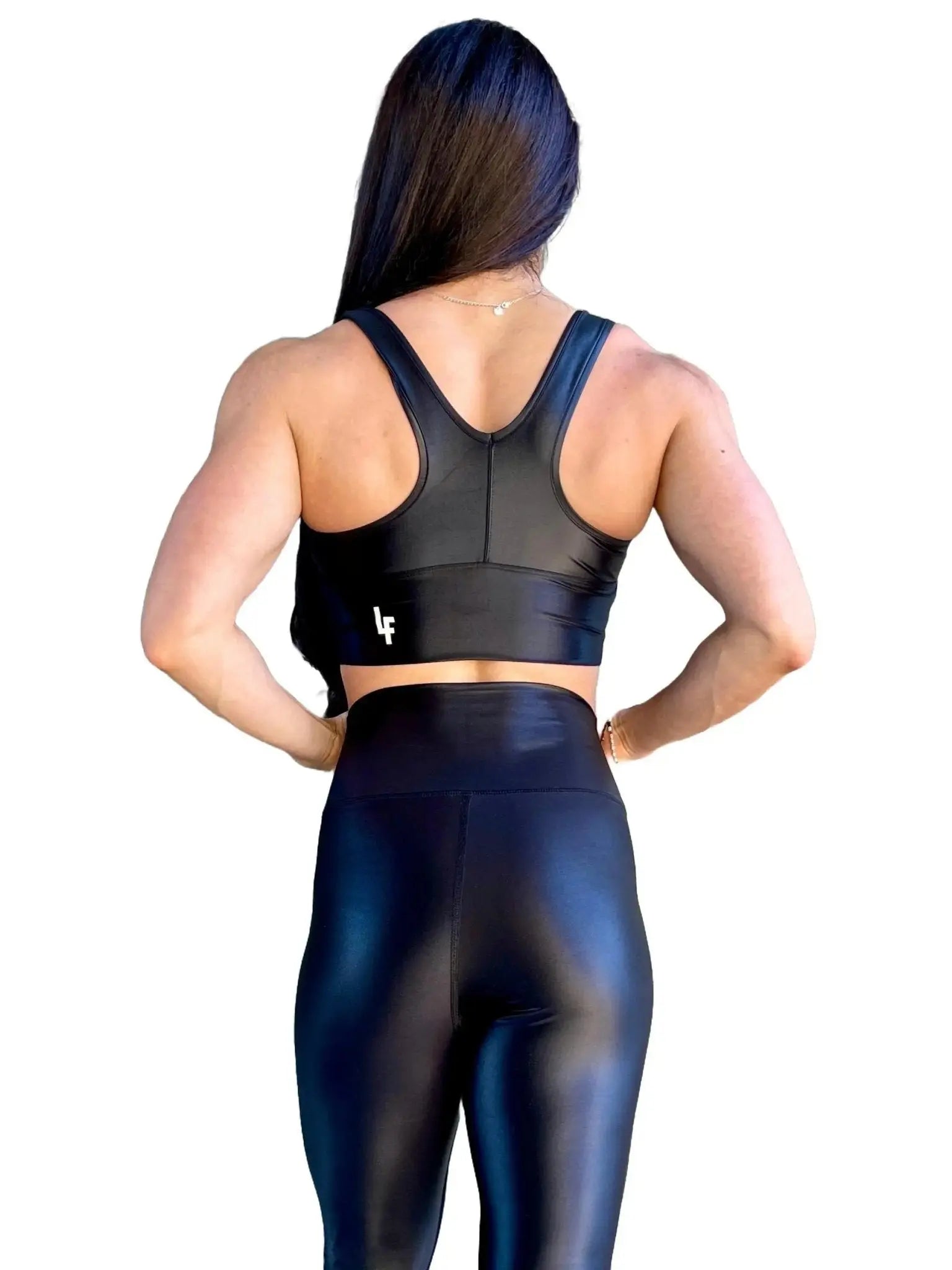 Mujer vistiendo el crop top brillante Top Adela Pearl Shine de LUXFEEL en color Negro Brillante, con escote en V y detalle fruncido en el pecho.