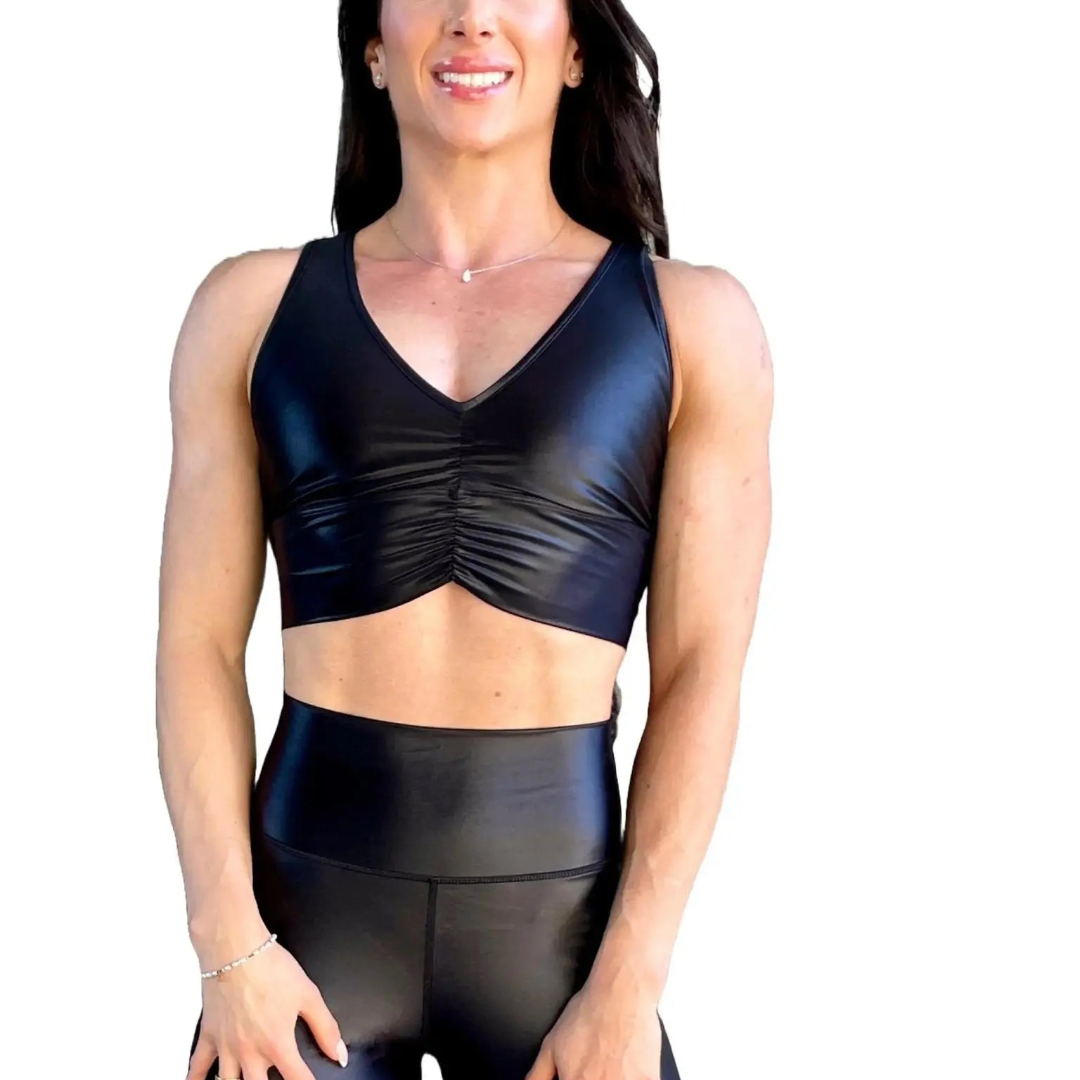 Mujer vistiendo el crop top brillante Top Adela Pearl Shine de LUXFEEL en color Negro Brillante, con escote en V y detalle fruncido en el pecho.