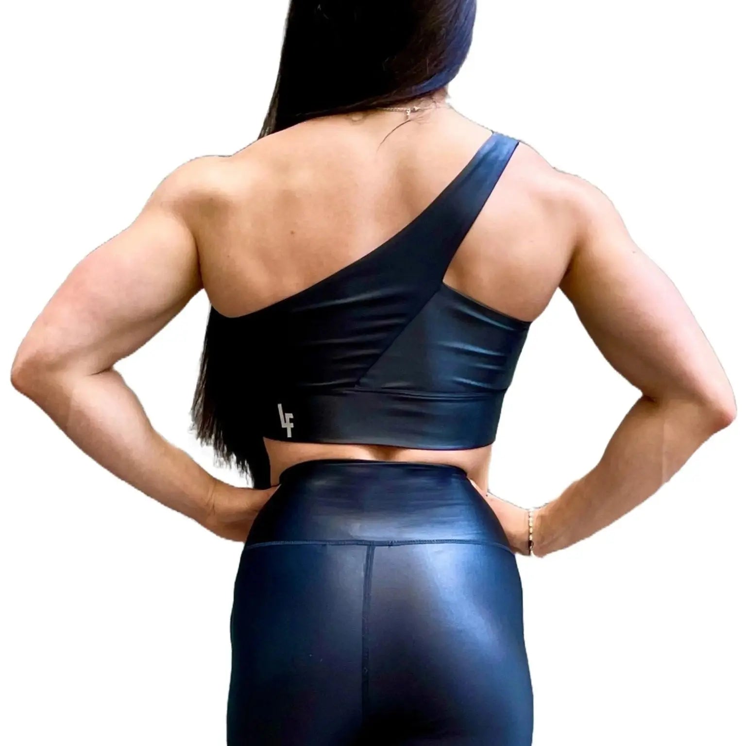 Mujer vistiendo el conjunto deportivo negro brillante de LUXFEEL, compuesto por el top asimétrico Carmela y el legging Pearl Shine