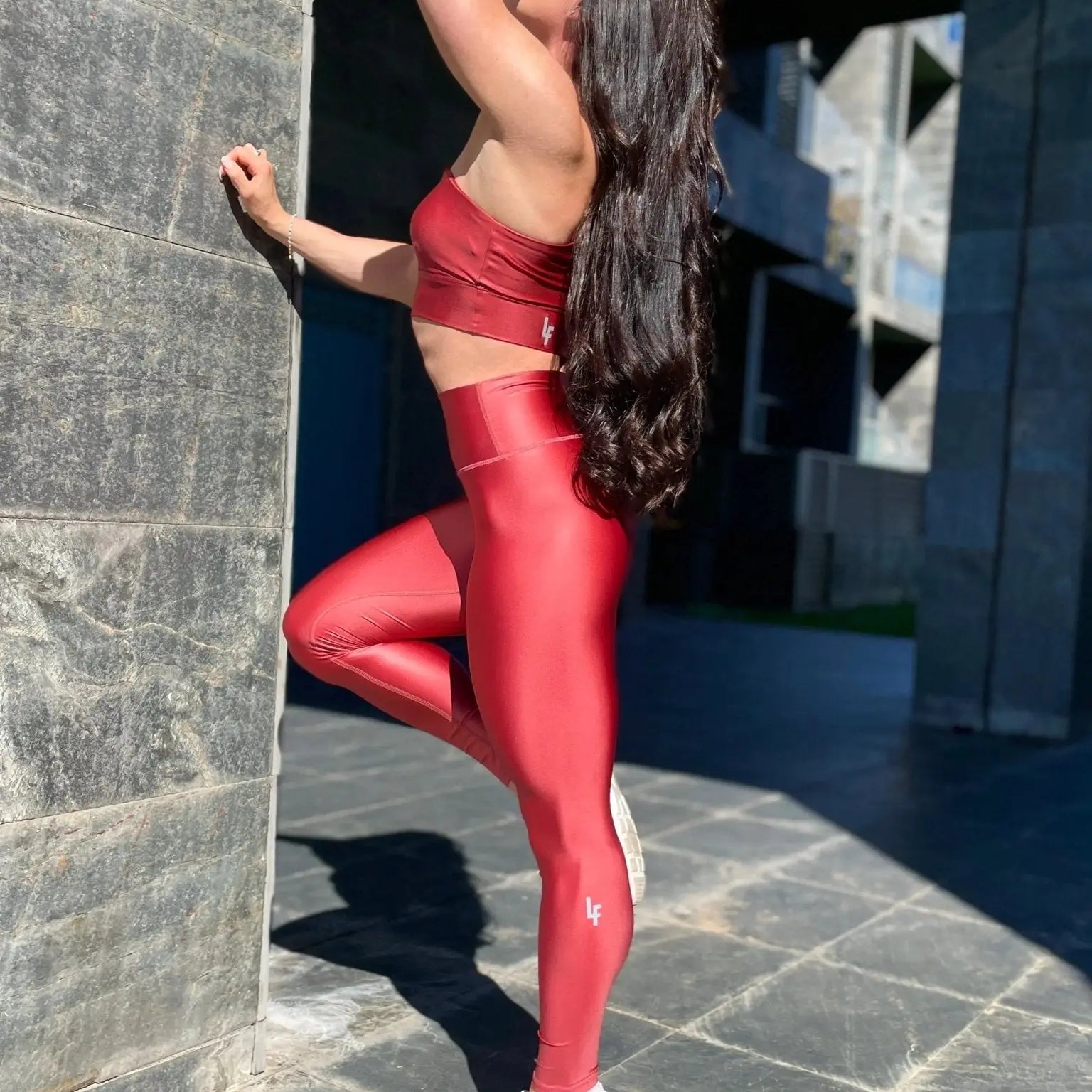 Mujer luciendo el top asimétrico brillante Top Carmela Pearl Shine de LUXFEEL en color Teja Brillante, con diseño de un solo hombro y apertura en el escote.