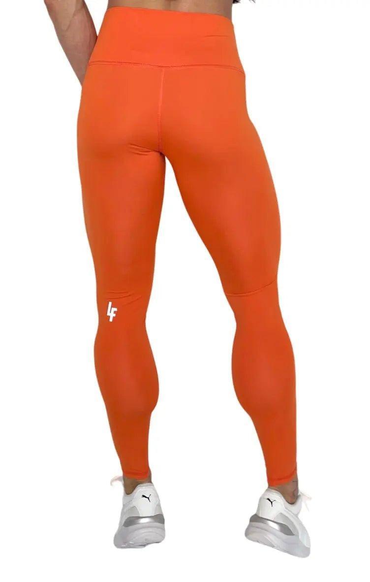 Mujer vistiendo los leggings compresivos de cintura alta Legging Myself de LUXFEEL en color Naranja, que ofrecen un efecto segunda piel.