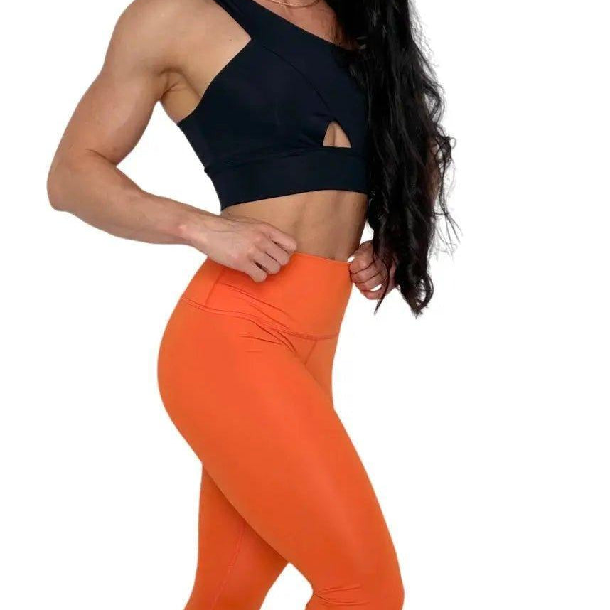 Mujer vistiendo los leggings compresivos de cintura alta Legging Myself de LUXFEEL en color Naranja, que ofrecen un efecto segunda piel.