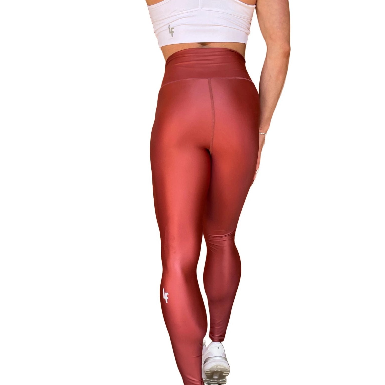 Mujer vistiendo los leggings brillantes de cintura alta Legging Pearl Shine de LUXFEEL en color Teja Brillante / Marron Brillante, con acabado efecto perla.