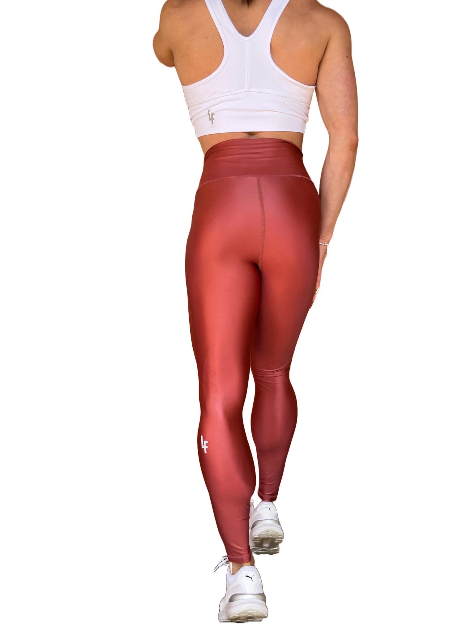 Mujer vistiendo los leggings brillantes de cintura alta Legging Pearl Shine de LUXFEEL en color Teja Brillante / Marron Brillante, con acabado efecto perla.