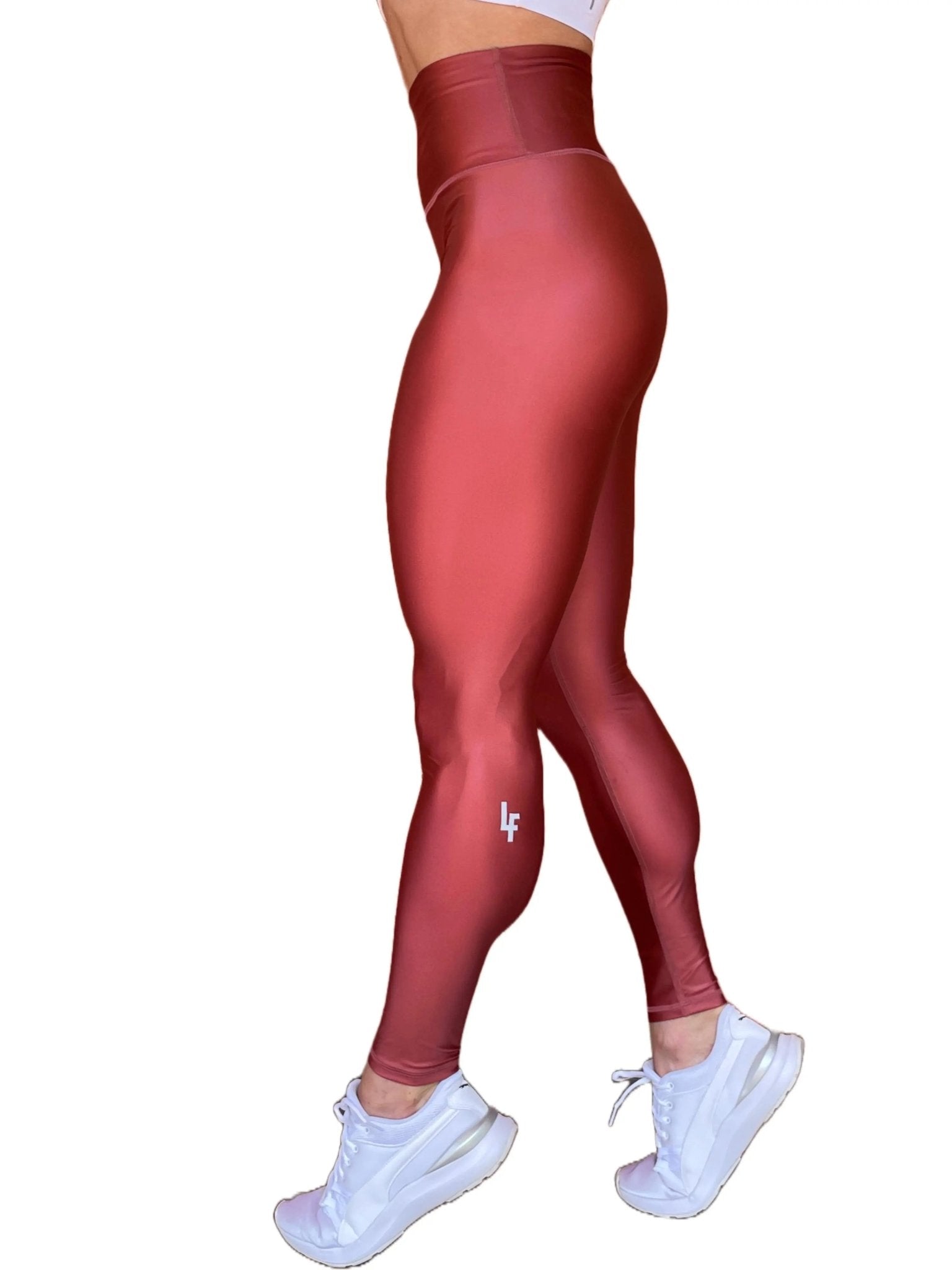 Mujer vistiendo los leggings brillantes de cintura alta Legging Pearl Shine de LUXFEEL en color Teja Brillante / Marron Brillante, con acabado efecto perla.