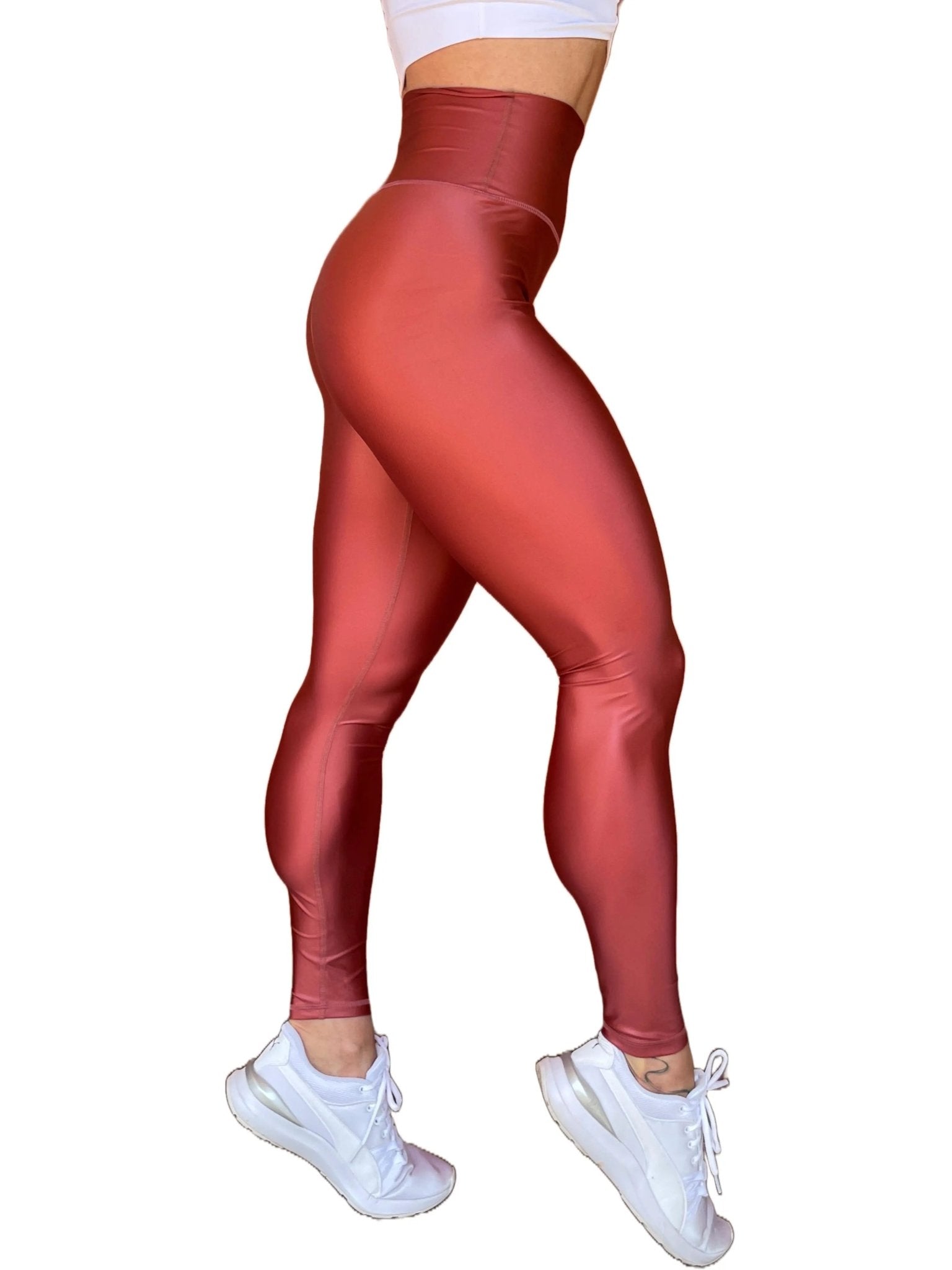 Mujer vistiendo los leggings brillantes de cintura alta Legging Pearl Shine de LUXFEEL en color Teja Brillante / Marron Brillante, con acabado efecto perla.