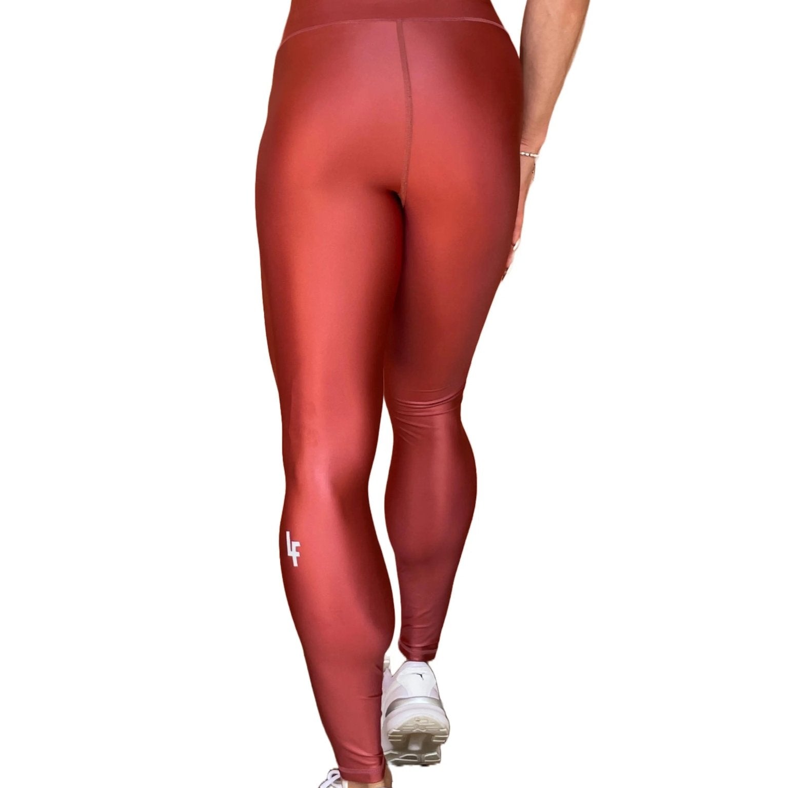 Mujer vistiendo los leggings brillantes de cintura alta Legging Pearl Shine de LUXFEEL en color Teja Brillante / Marron Brillante, con acabado efecto perla.