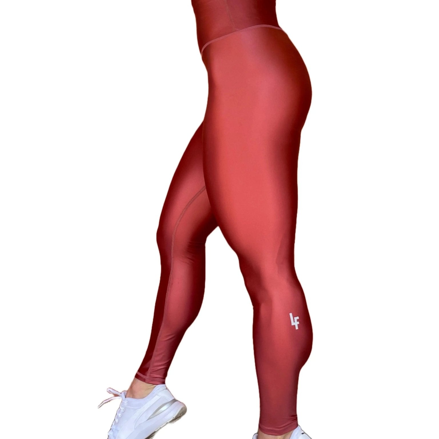 Mujer vistiendo los leggings brillantes de cintura alta Legging Pearl Shine de LUXFEEL en color Teja Brillante / Marron Brillante, con acabado efecto perla.