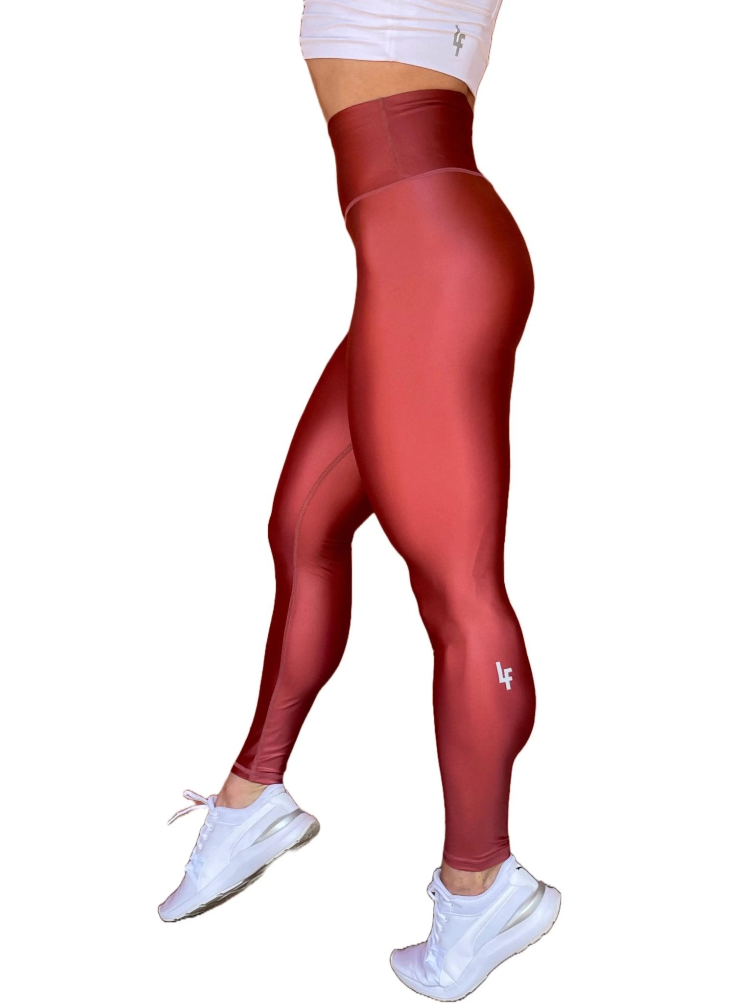 Mujer vistiendo los leggings brillantes de cintura alta Legging Pearl Shine de LUXFEEL en color Teja Brillante / Marron Brillante, con acabado efecto perla.