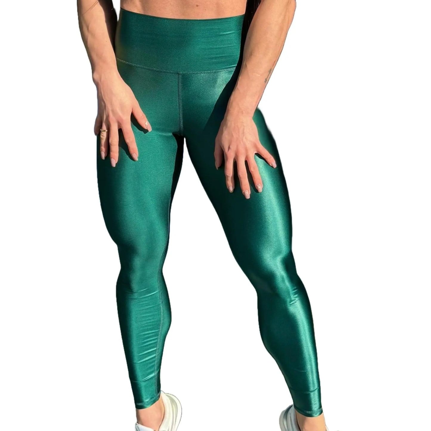 Mujer vistiendo los leggings brillantes de cintura alta Legging Pearl Shine de LUXFEEL en color Verde Botella Brillante, con acabado efecto perla.