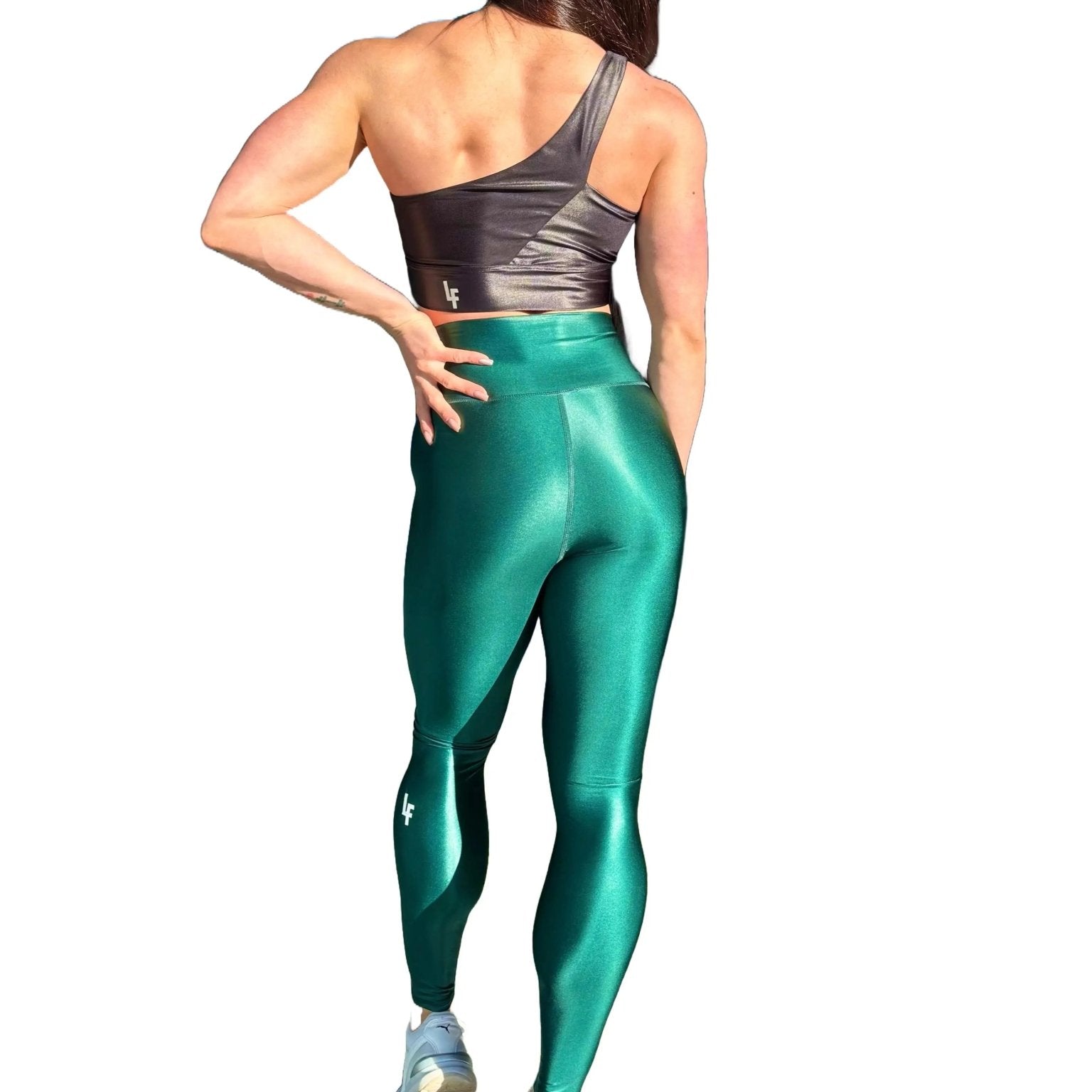 Mujer vistiendo los leggings brillantes de cintura alta Legging Pearl Shine de LUXFEEL en color Verde Botella Brillante, con acabado efecto perla.