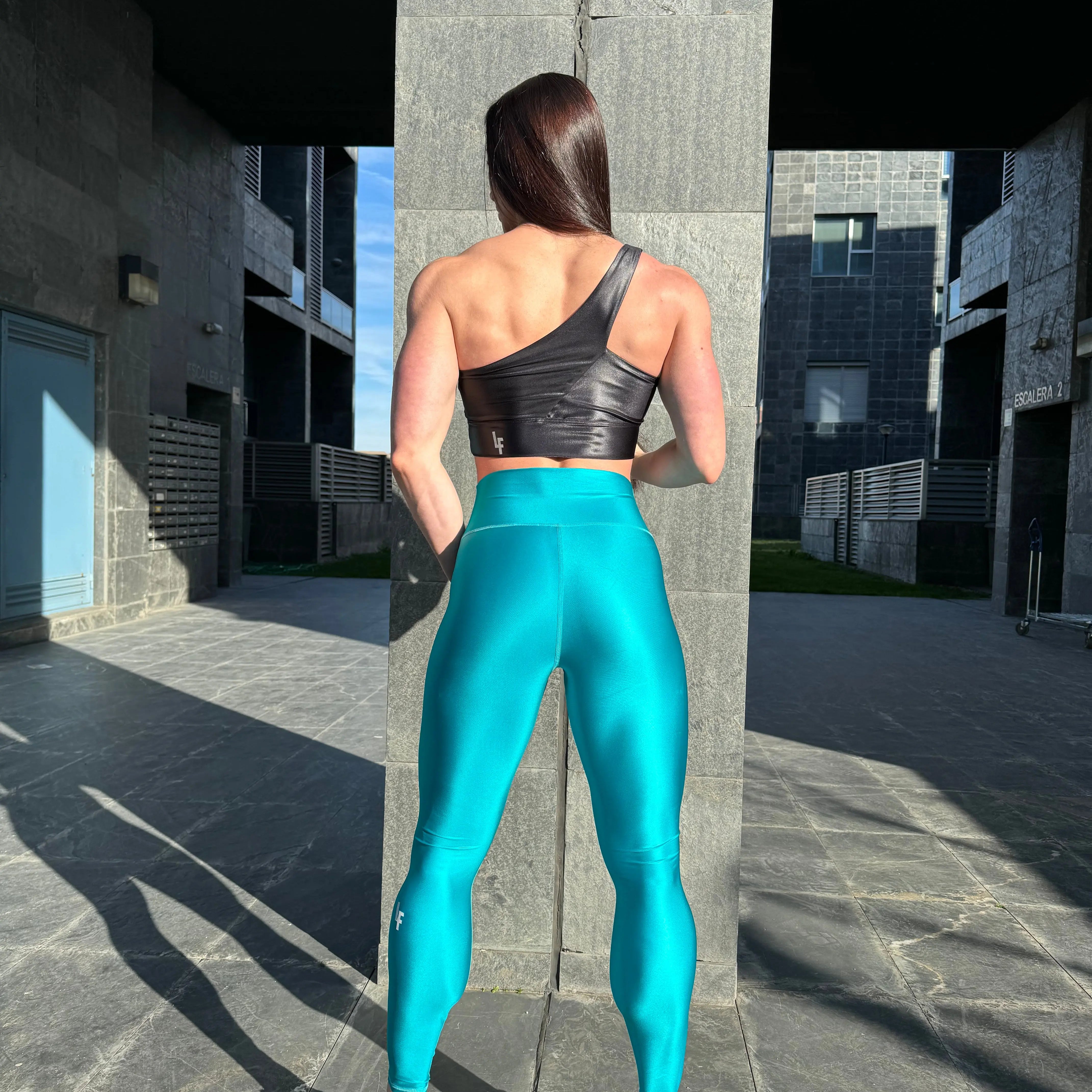 Mujer vistiendo los leggings brillantes de cintura alta Legging Pearl Shine de LUXFEEL en color Azul Capri Brillante, con acabado efecto perla.