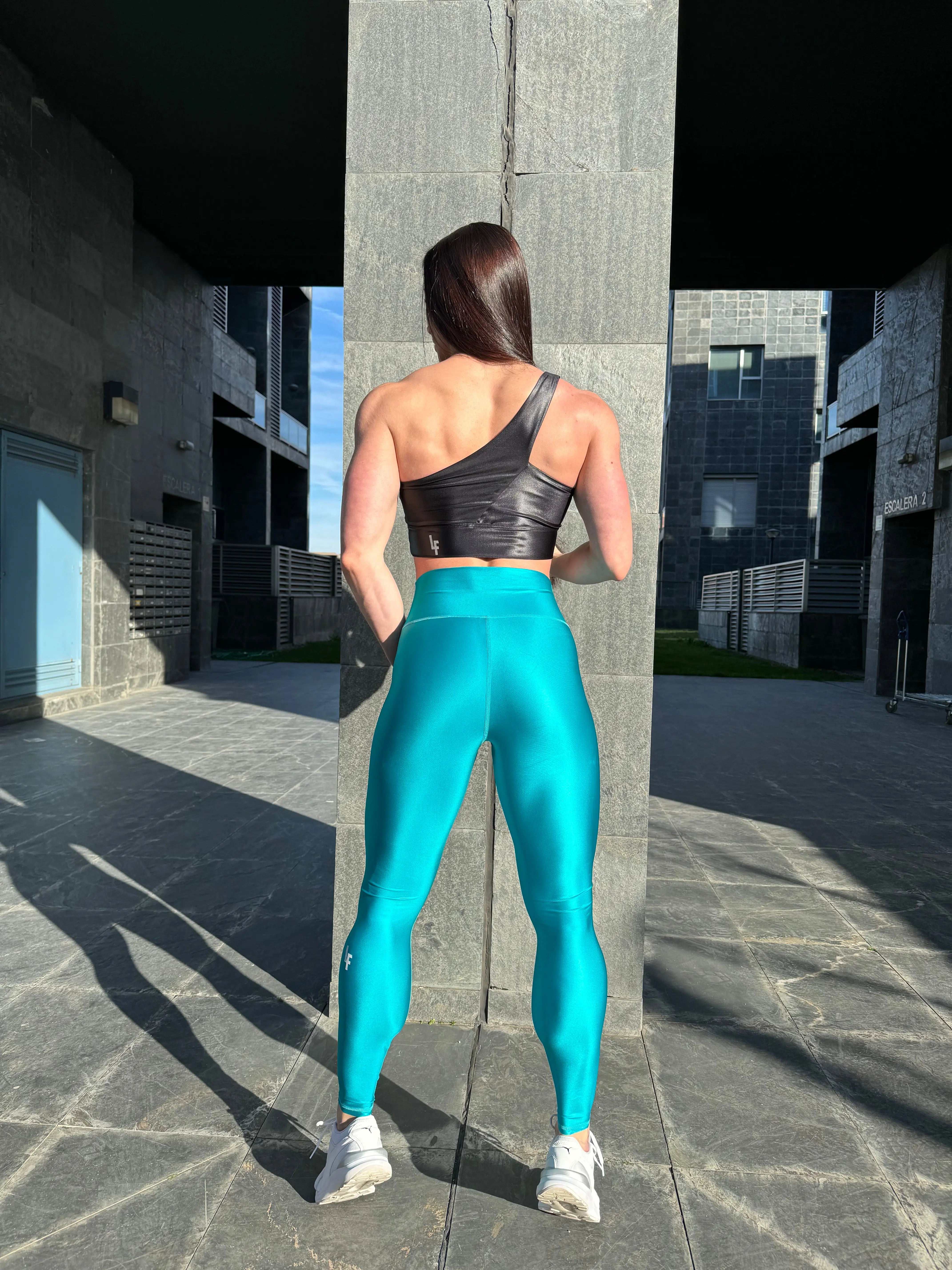 Mujer vistiendo los leggings brillantes de cintura alta Legging Pearl Shine de LUXFEEL en color Azul Capri Brillante, con acabado efecto perla.
