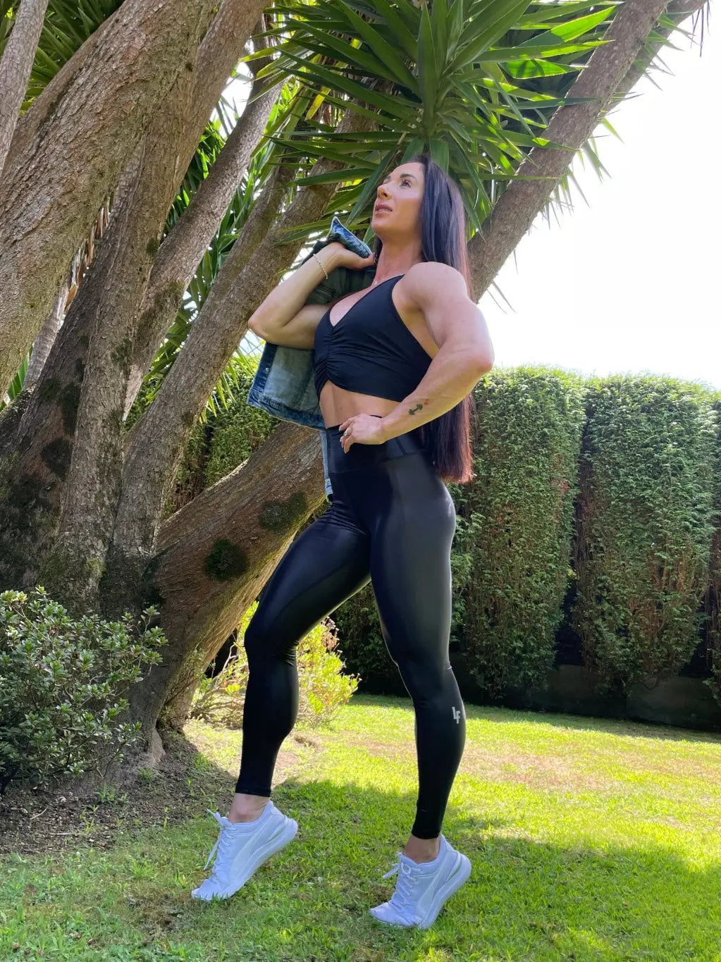 Mujer vistiendo los leggings brillantes de cintura alta Legging Pearl Shine de LUXFEEL en color Negro Brillante, con acabado efecto perla.