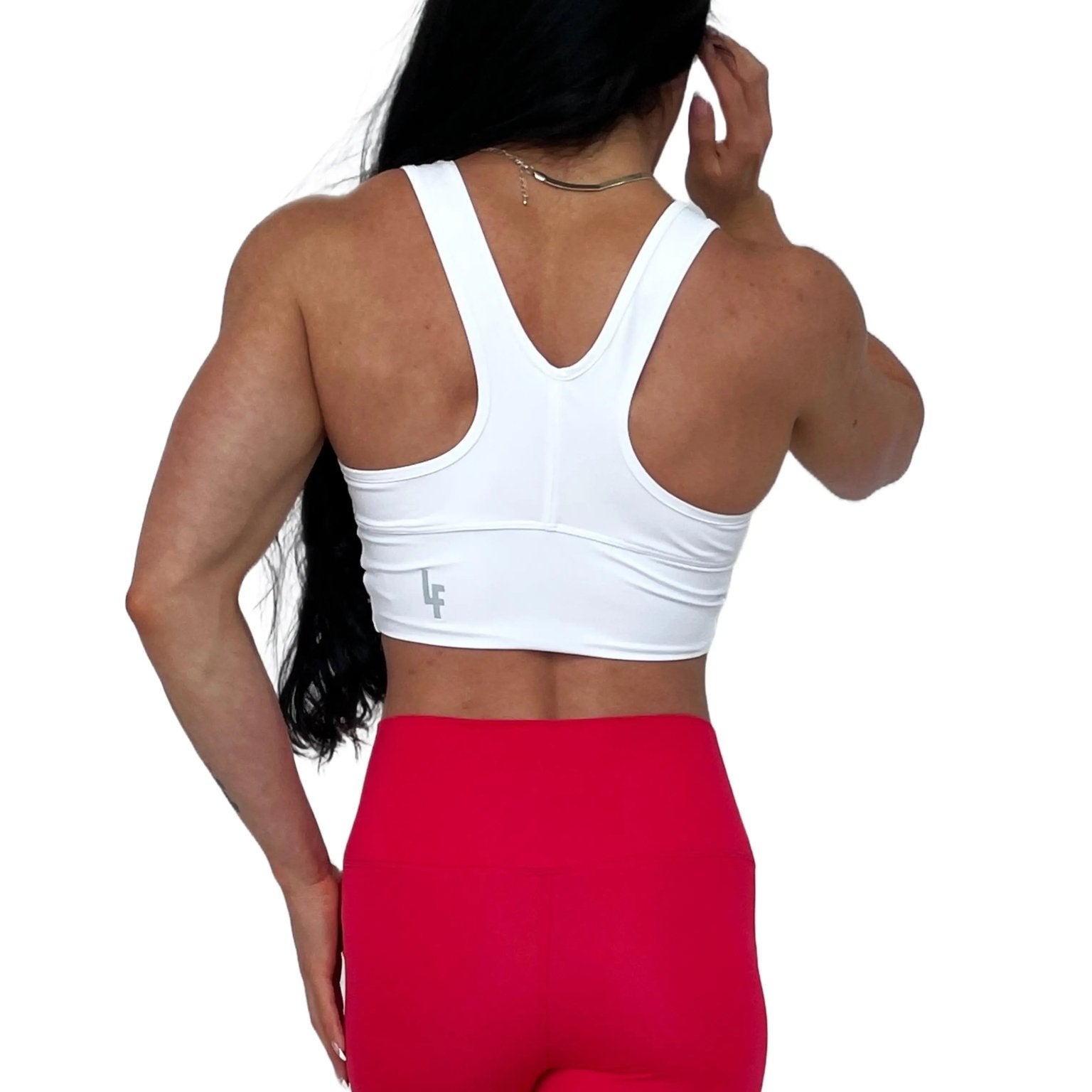 Mujer vistiendo el crop top deportivo Top Adela de LUXFEEL en color Blanco, con escote en V y detalle fruncido en el pecho.