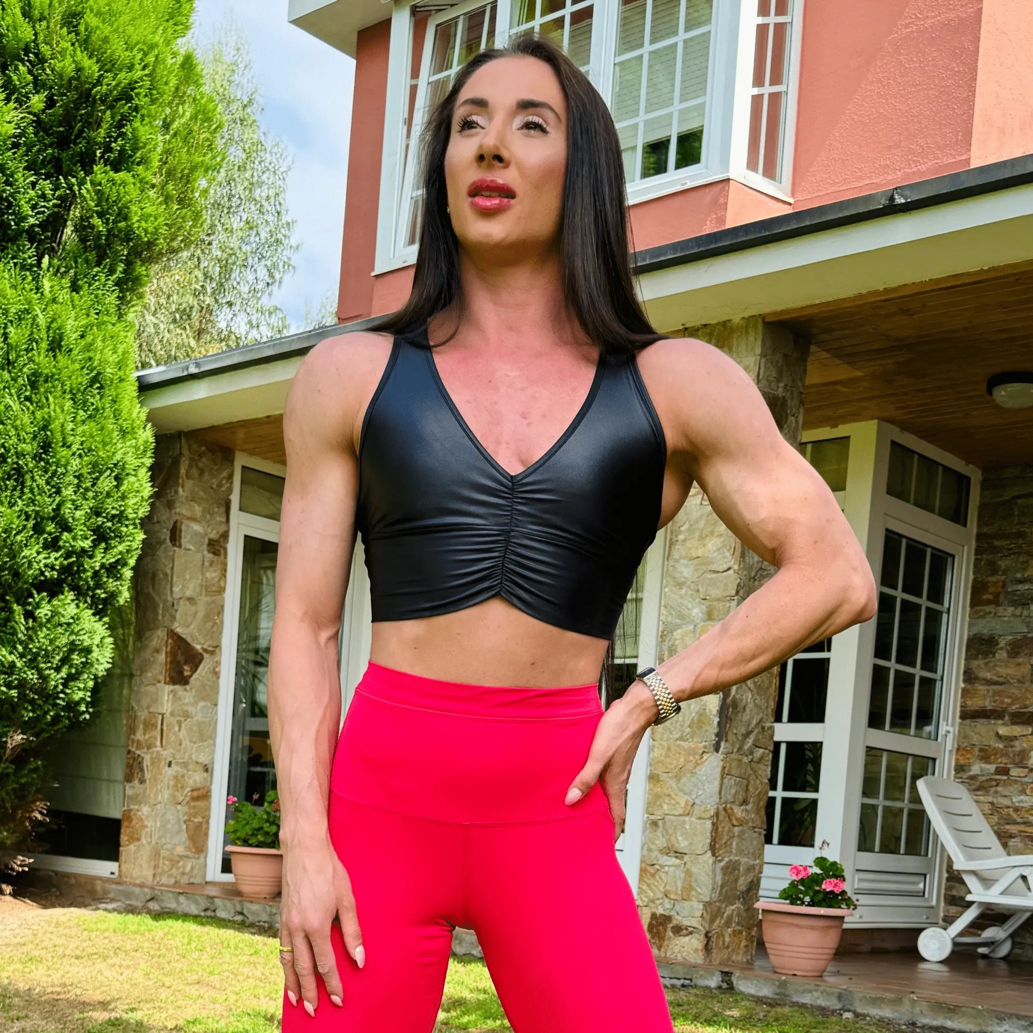 Mujer vistiendo el crop top brillante Top Adela Pearl Shine de LUXFEEL en color Negro Brillante, con escote en V y detalle fruncido en el pecho.