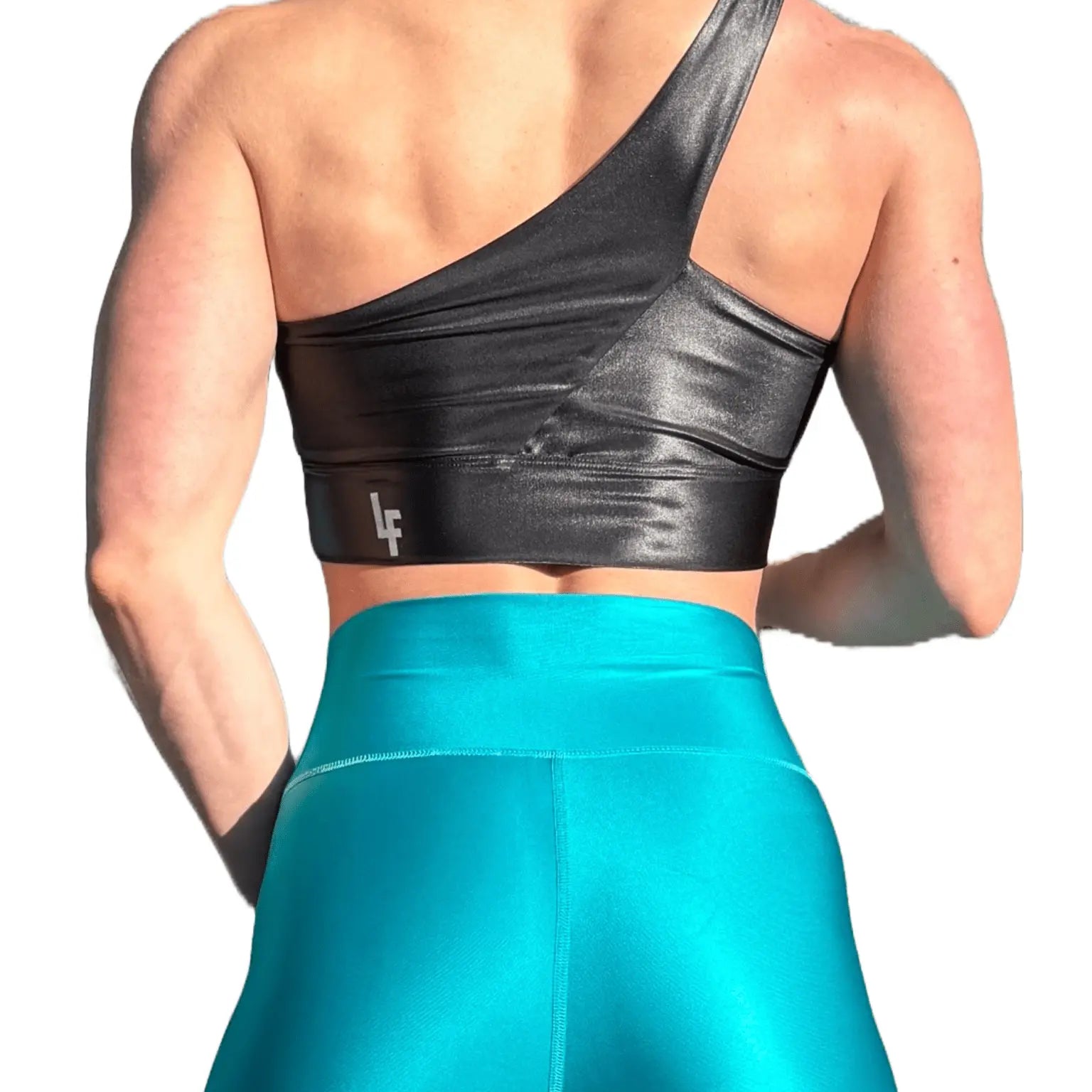 Mujer luciendo el top asimétrico brillante Top Carmela Pearl Shine de LUXFEEL en color Negro Brillante, con diseño de un solo hombro y apertura en el escote.