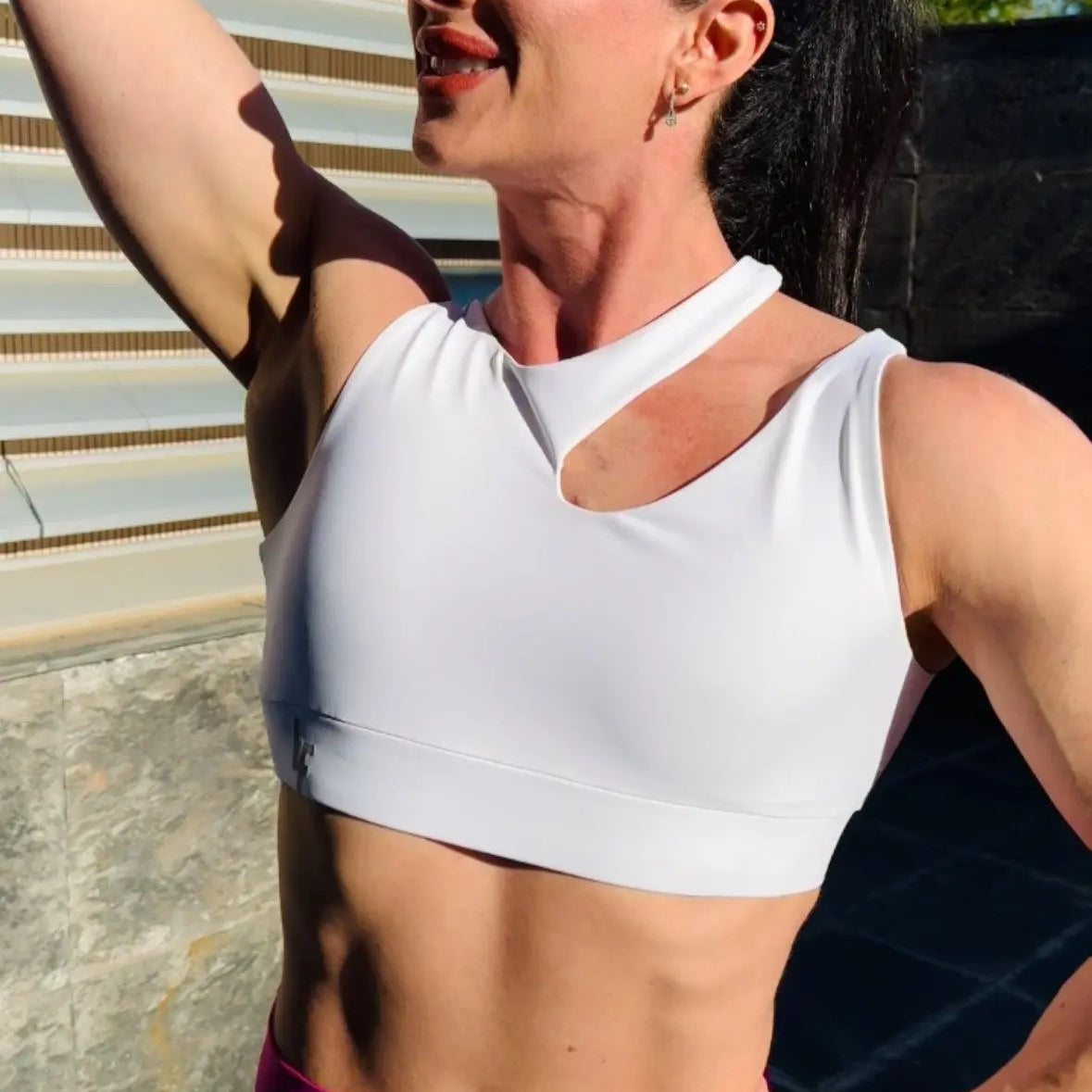 Mujer luciendo el top asimétrico Top Vanesa de LUXFEEL en color Blanco, con un diseño de apertura en el hombro y soporte extra.