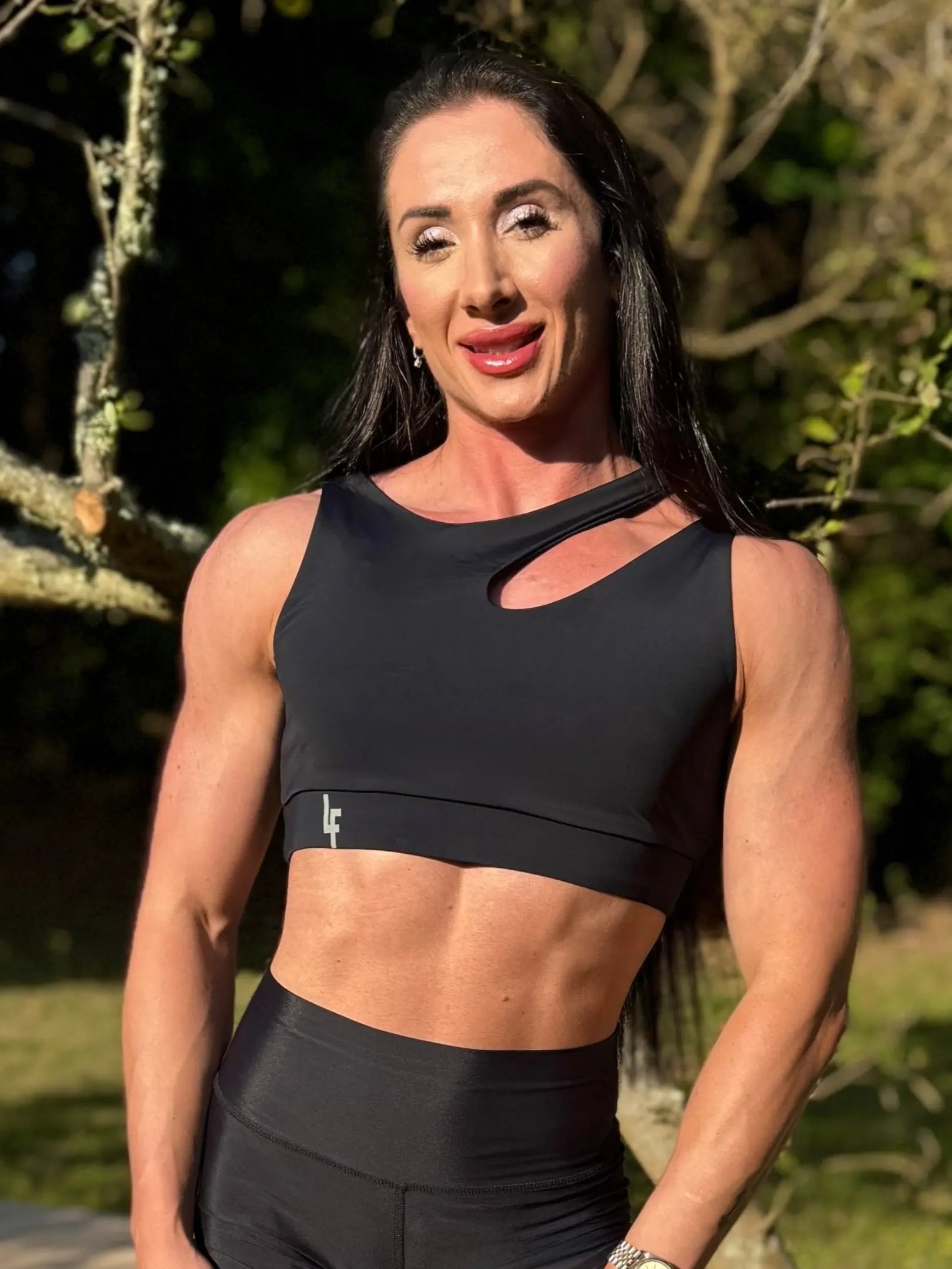 Modelo en la naturaleza mostrando Top Vanesa (foto de frente) de LUXFEEL en color negro, con un diseño de apertura en el hombro y soporte extra.