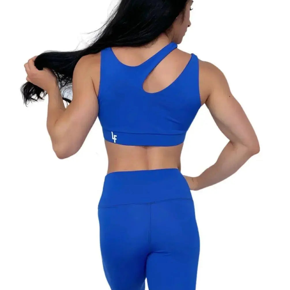 Mujer vistiendo el conjunto deportivo azul de LUXFEEL, compuesto por el top asimétrico Vanesa y el legging escultor Myself.