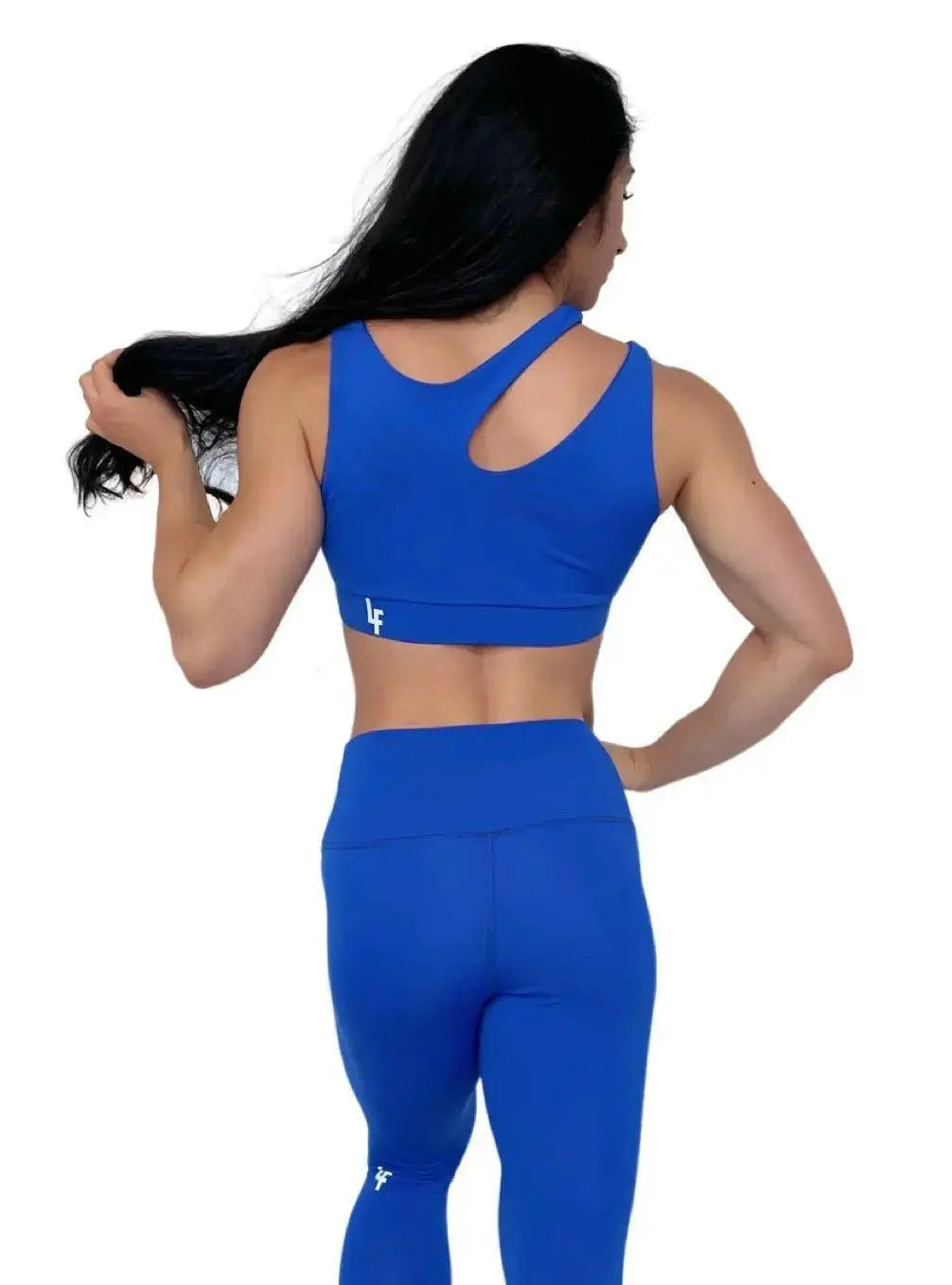 Mujer vistiendo el conjunto deportivo azul de LUXFEEL, compuesto por el top asimétrico Vanesa y el legging escultor Myself.