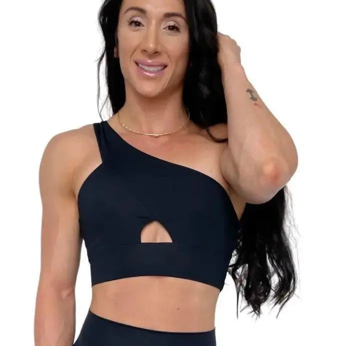 Mujer vistiendo el conjunto deportivo negro de LUXFEEL, compuesto por el top asimétrico Carmela y el legging escultor Myself.