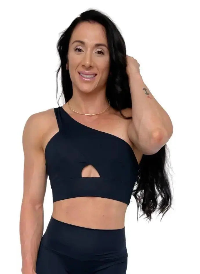 Mujer vistiendo el conjunto deportivo negro de LUXFEEL, compuesto por el top asimétrico Carmela y el legging escultor Myself.