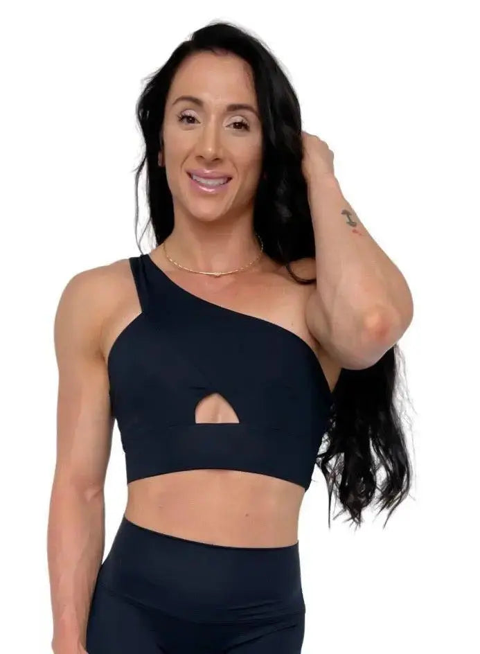 Mujer vistiendo el conjunto deportivo negro de LUXFEEL, compuesto por el top asimétrico Carmela y el legging escultor Myself.