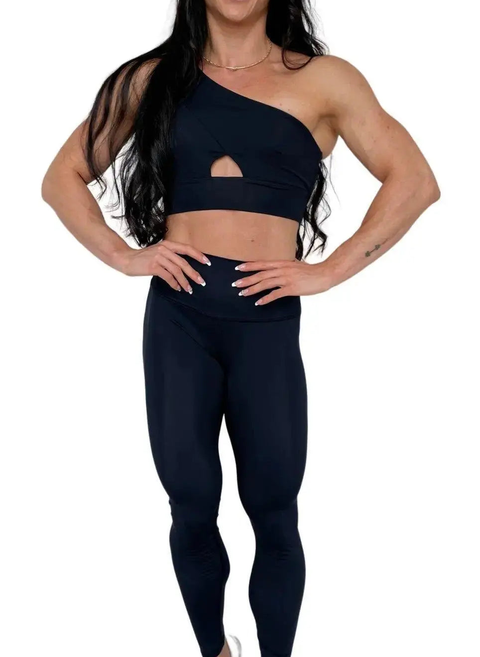 Mujer vistiendo el conjunto deportivo negro de LUXFEEL, compuesto por el top asimétrico Carmela y el legging escultor Myself.