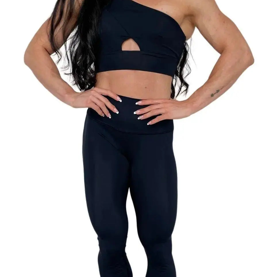 Mujer vistiendo el conjunto deportivo negro de LUXFEEL, compuesto por el top asimétrico Carmela y el legging escultor Myself.