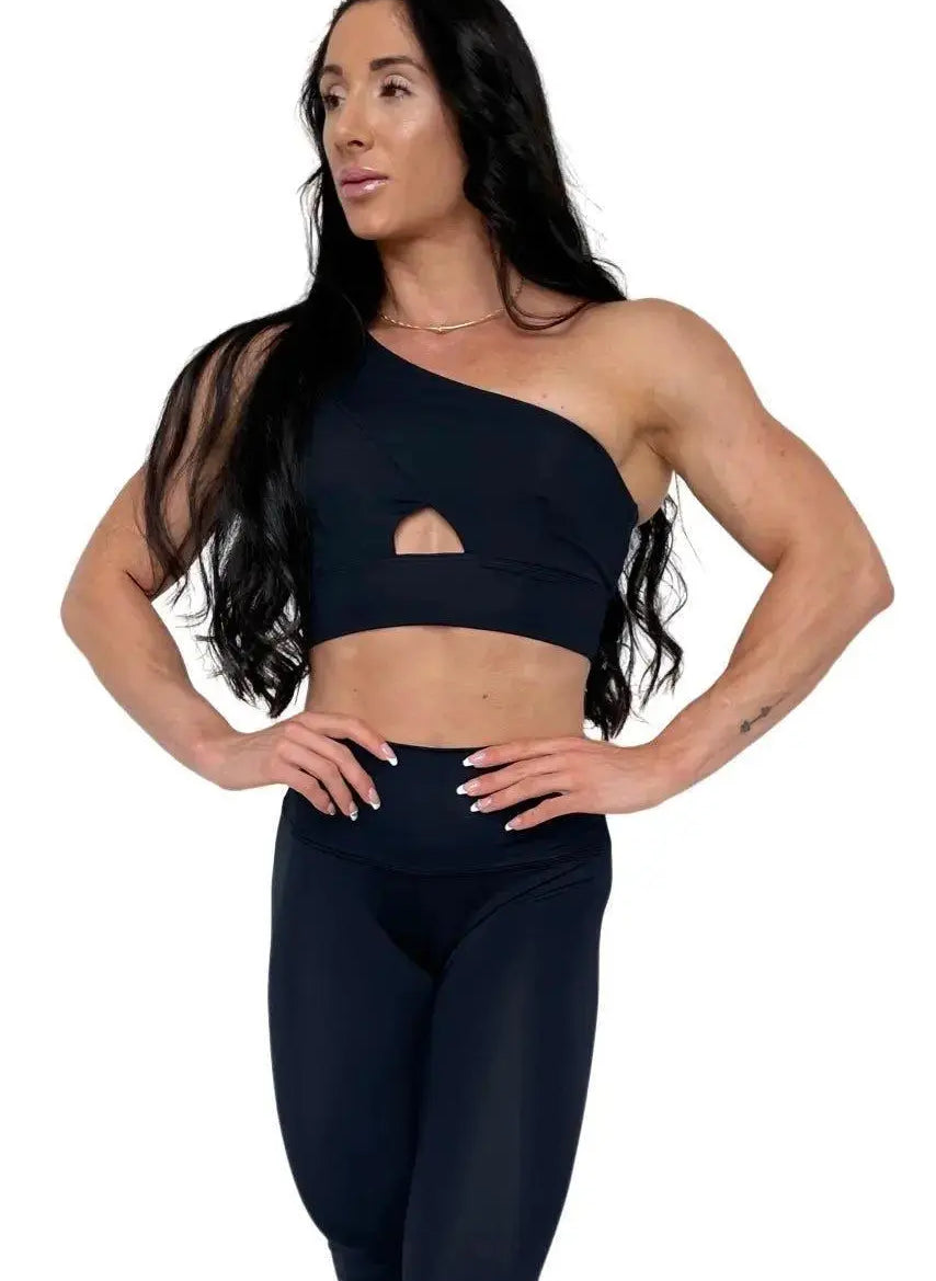 Mujer vistiendo el conjunto deportivo negro de LUXFEEL, compuesto por el top asimétrico Carmela y el legging escultor Myself.