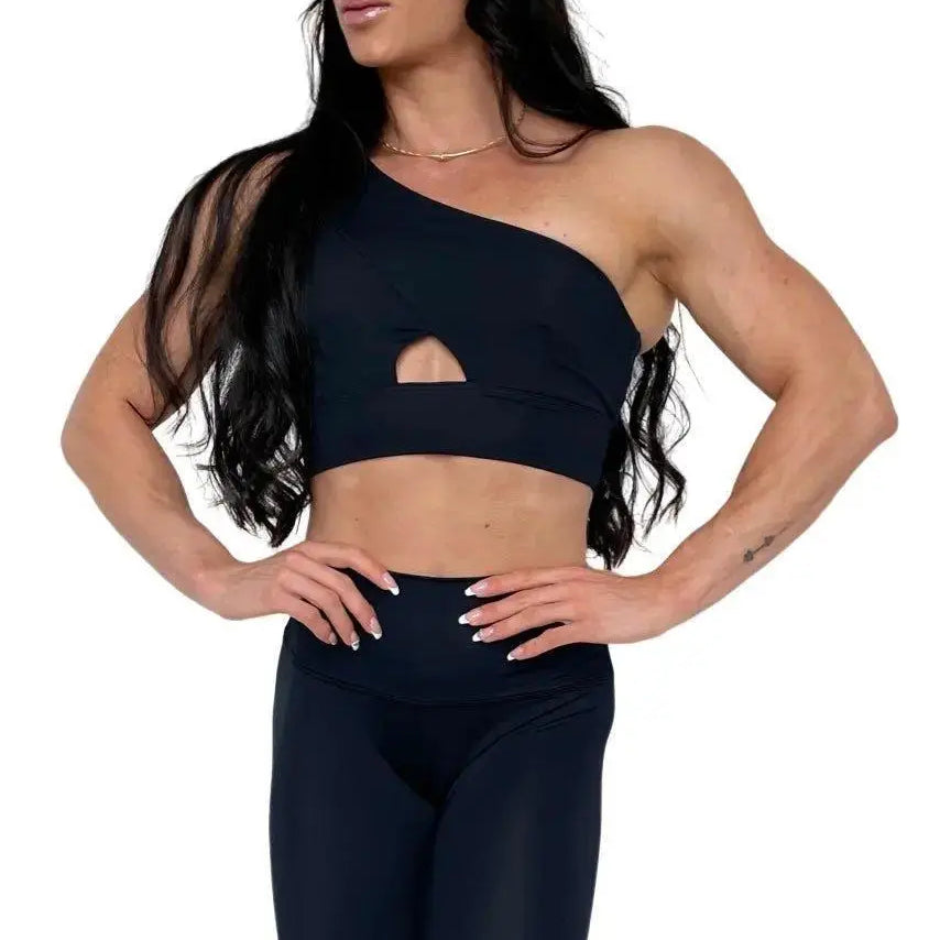 Mujer vistiendo el conjunto deportivo negro de LUXFEEL, compuesto por el top asimétrico Carmela y el legging escultor Myself.