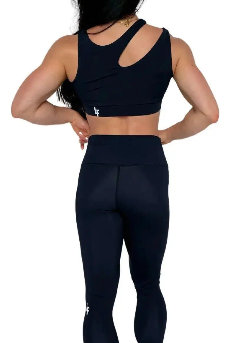 Mujer luciendo el top asimétrico Top Vanesa de LUXFEEL en color Negro, con un diseño de apertura en el hombro y soporte extra.