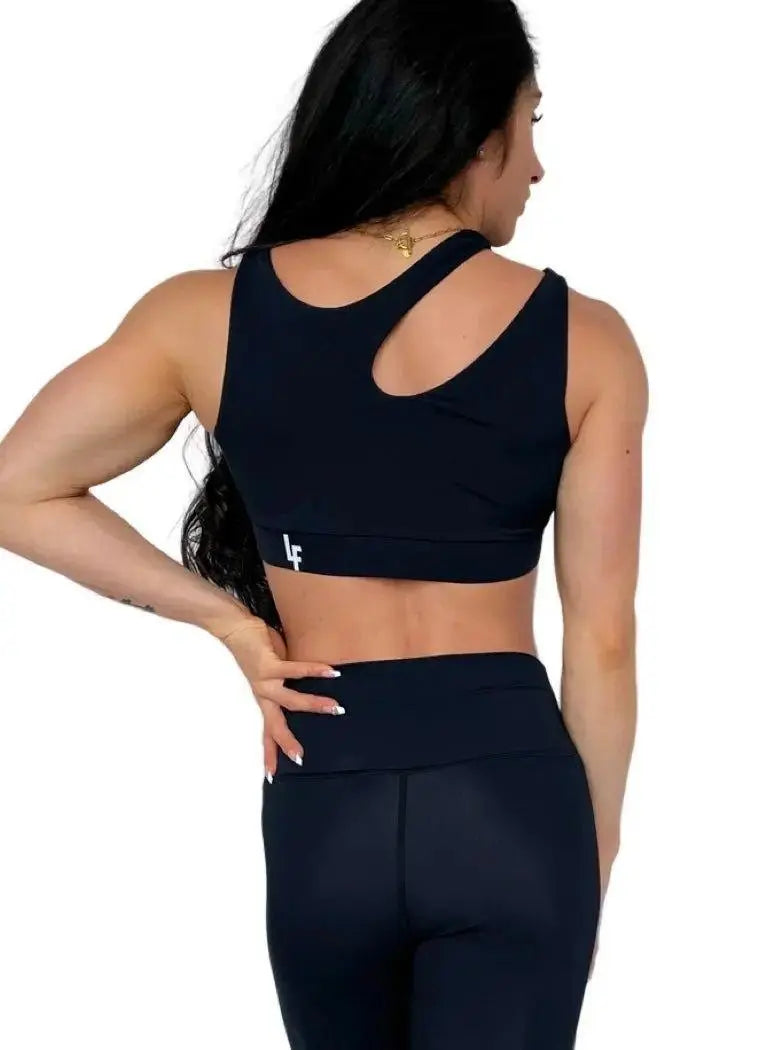 Mujer luciendo el top asimétrico Top Vanesa de LUXFEEL en color Negro, con un diseño de apertura en el hombro y soporte extra.