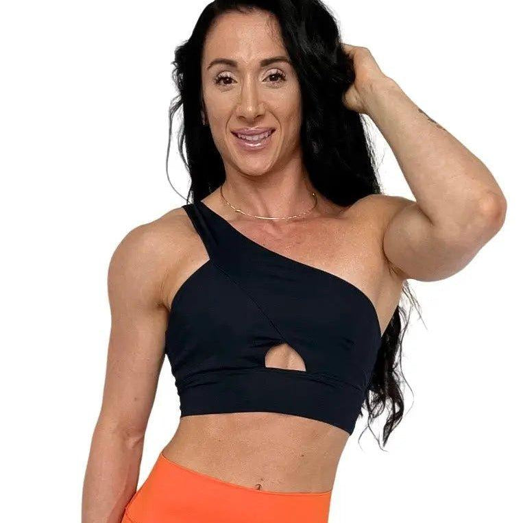 Mujer luciendo el top asimétrico Top Carmela de LUXFEEL en color Negro, con diseño de un solo hombro y apertura en el escote